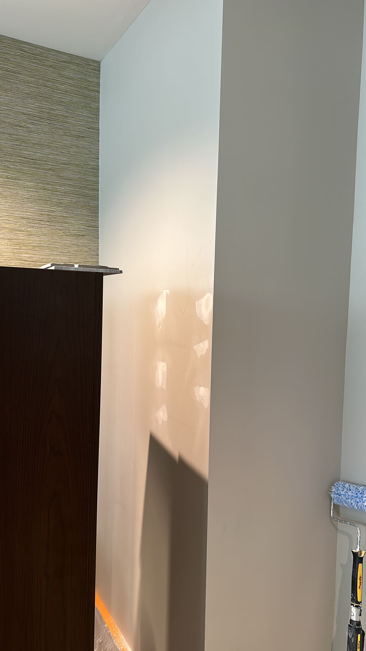 Wall partially painted light blue; brown cabinet on the left.