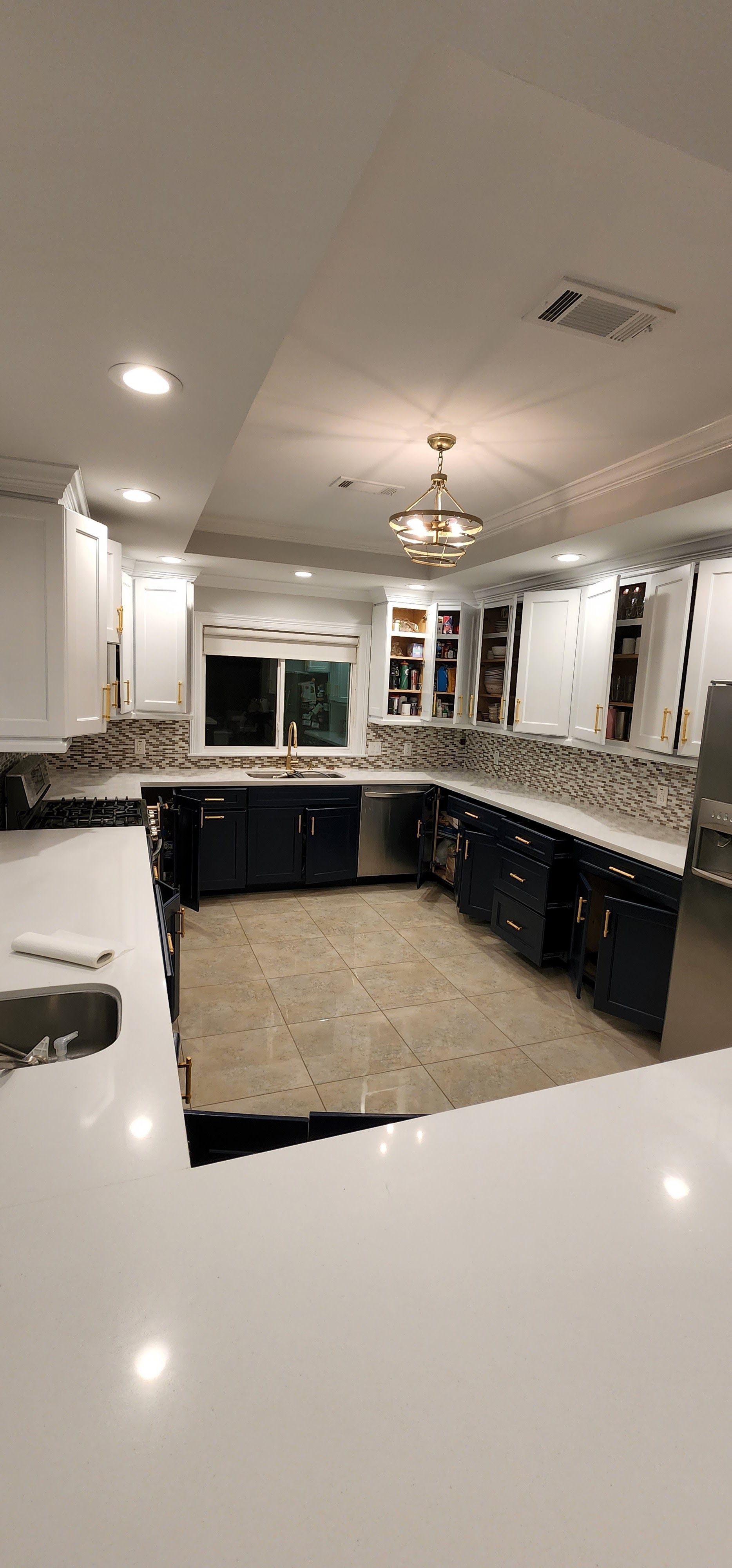 Kitchen remodel with white countertops, dark blue cabinets, and a decorative backsplash.