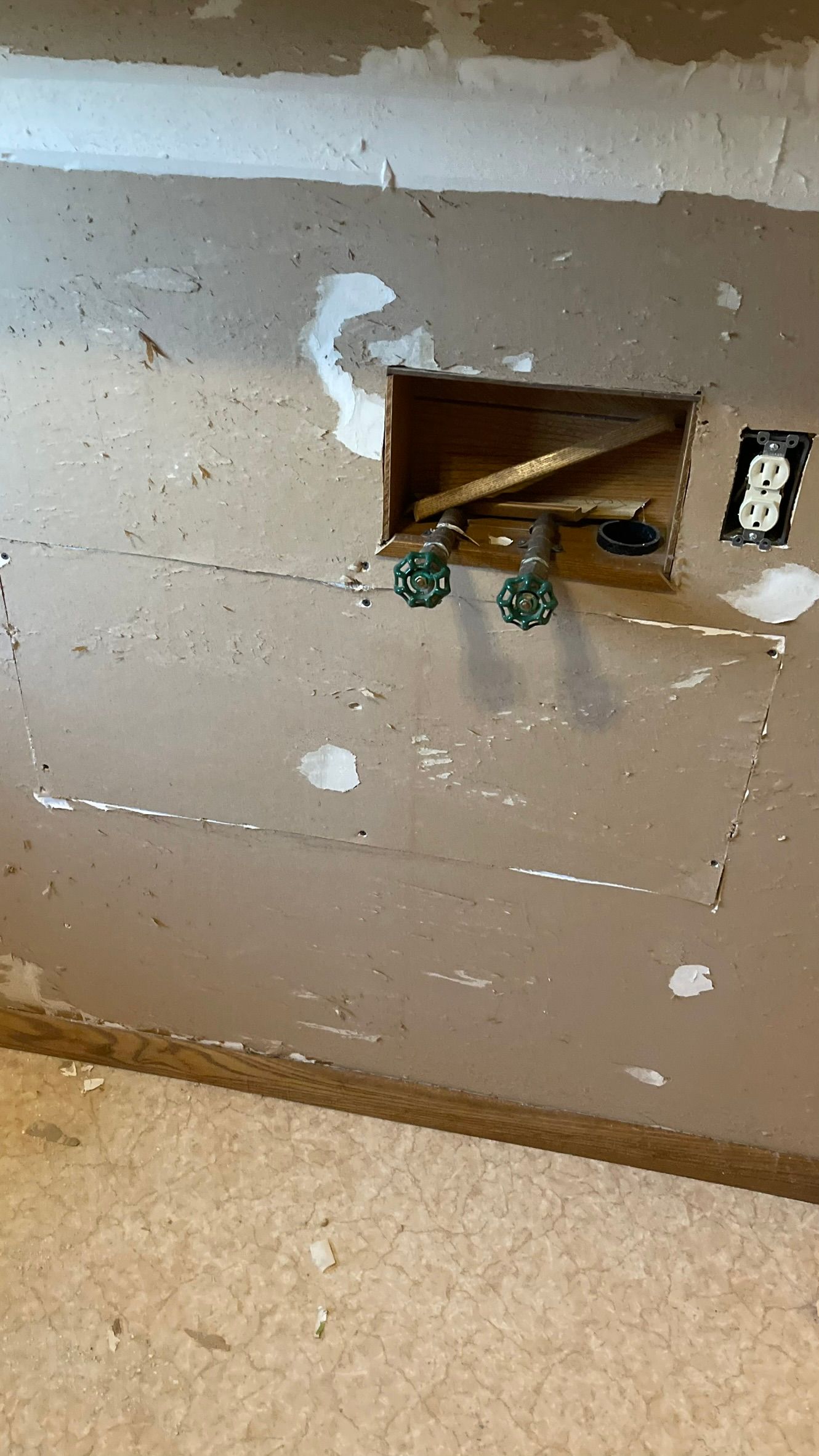 Wall with exposed plumbing and electrical outlet, drywall removed, brown and white.