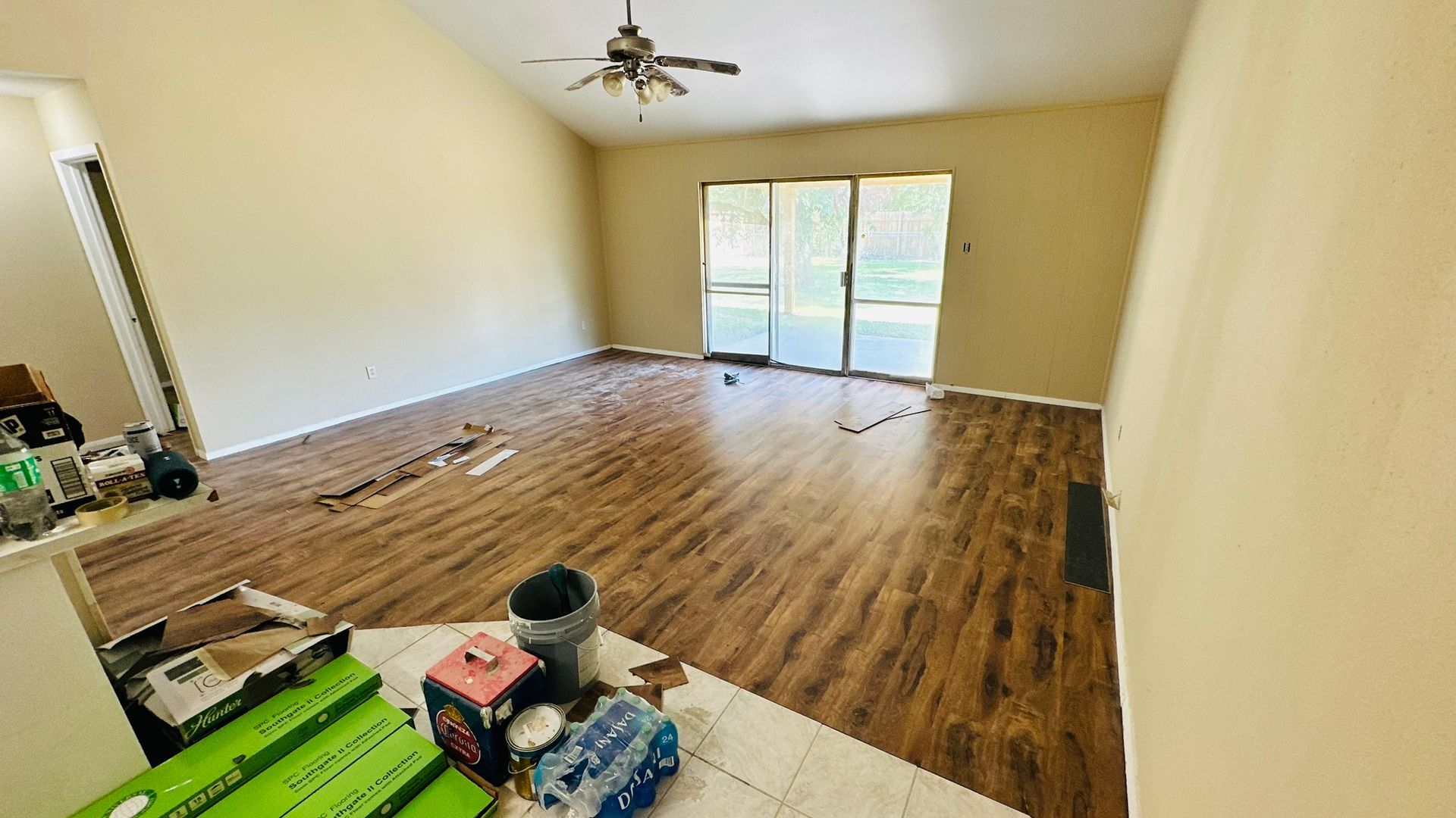Empty living room with wood-look flooring, beige walls, and a sliding glass door.