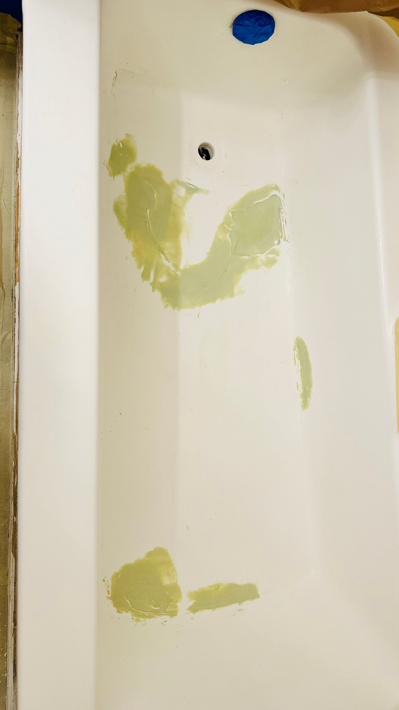 White bathtub with patches of green filler.