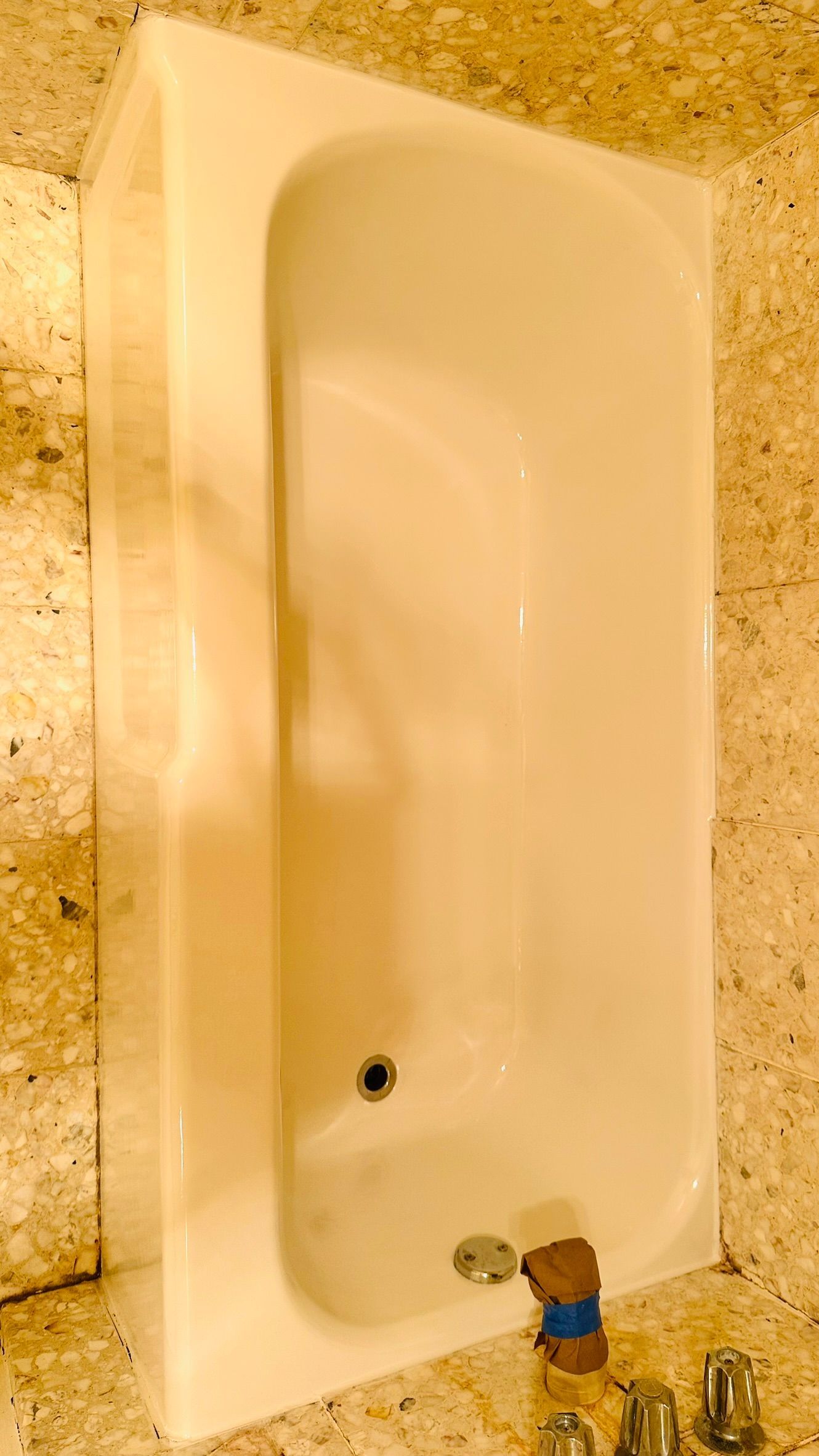 White rectangular bathtub set against a textured, light-colored wall.