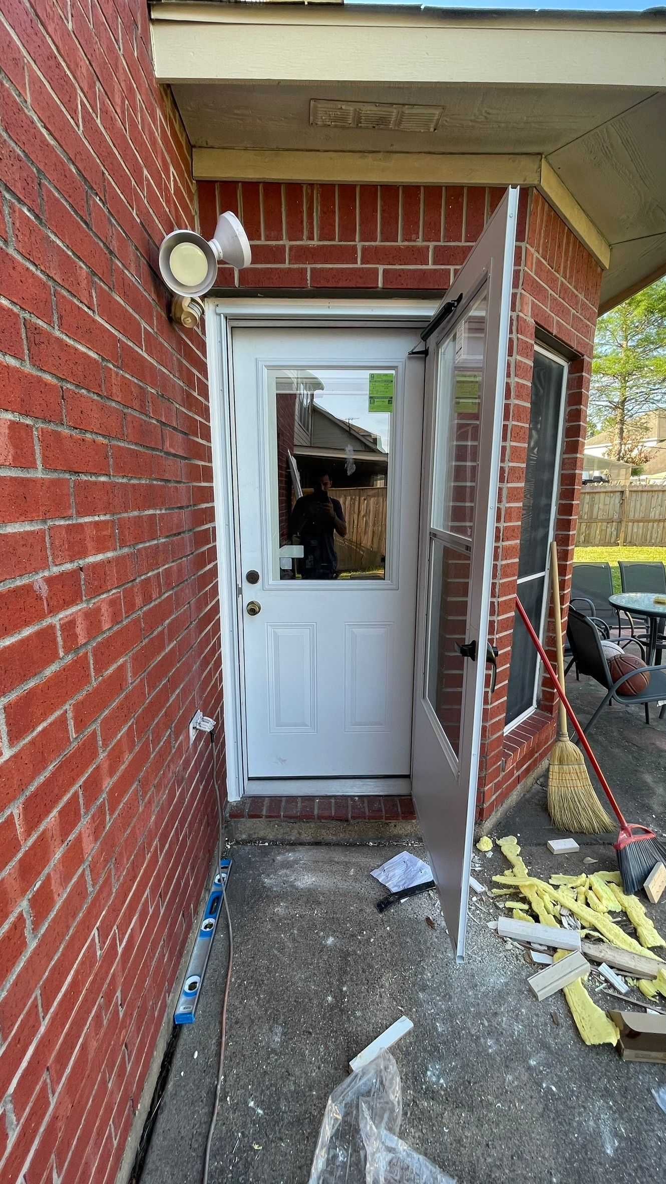 White exterior door with glass panes and a side window, brick building.