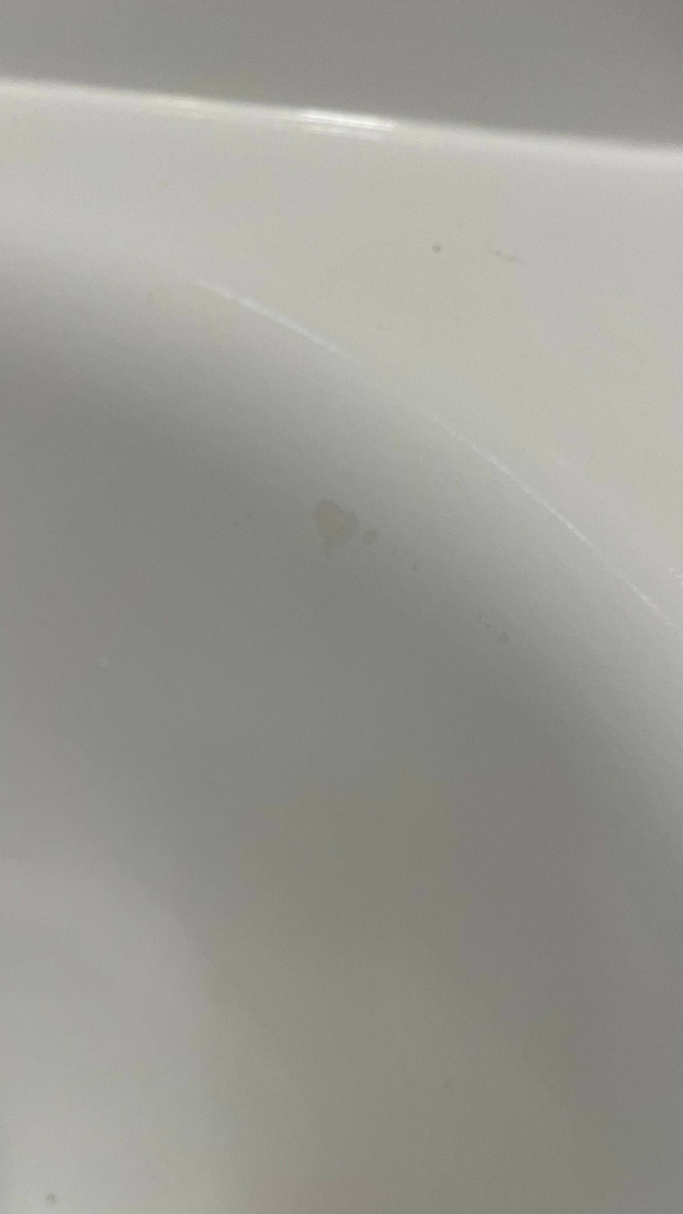 Close-up of a white, curved surface with a small, light-colored stain.