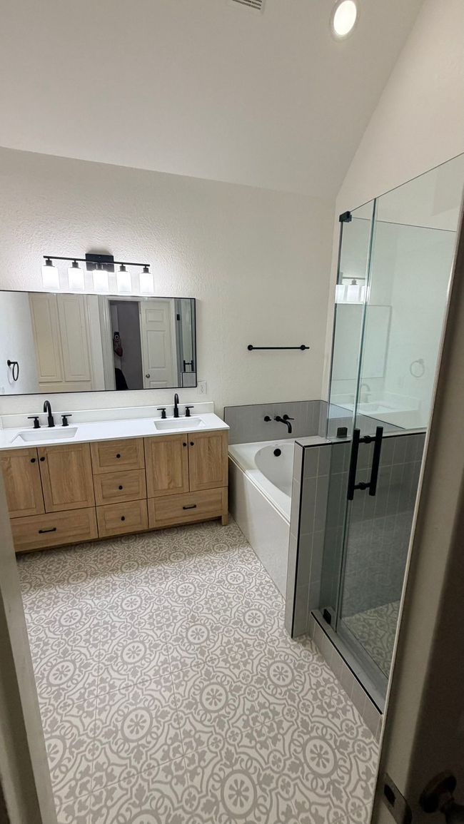 Modern bathroom with floating sink, brown cabinet, mirror, and beige door.