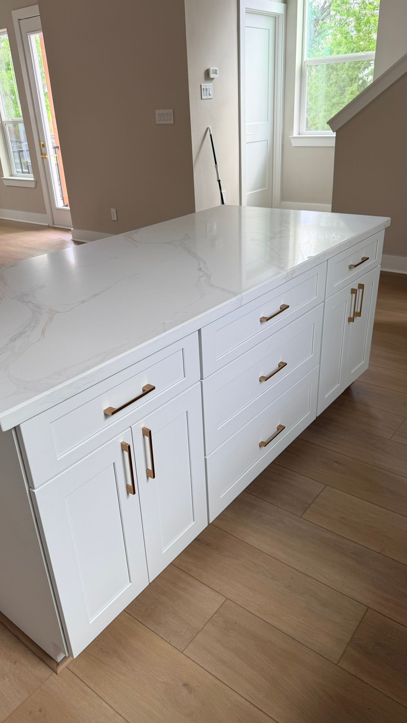 White kitchen with gold fixtures, including a faucet and cabinet hardware, and a farmhouse sink.