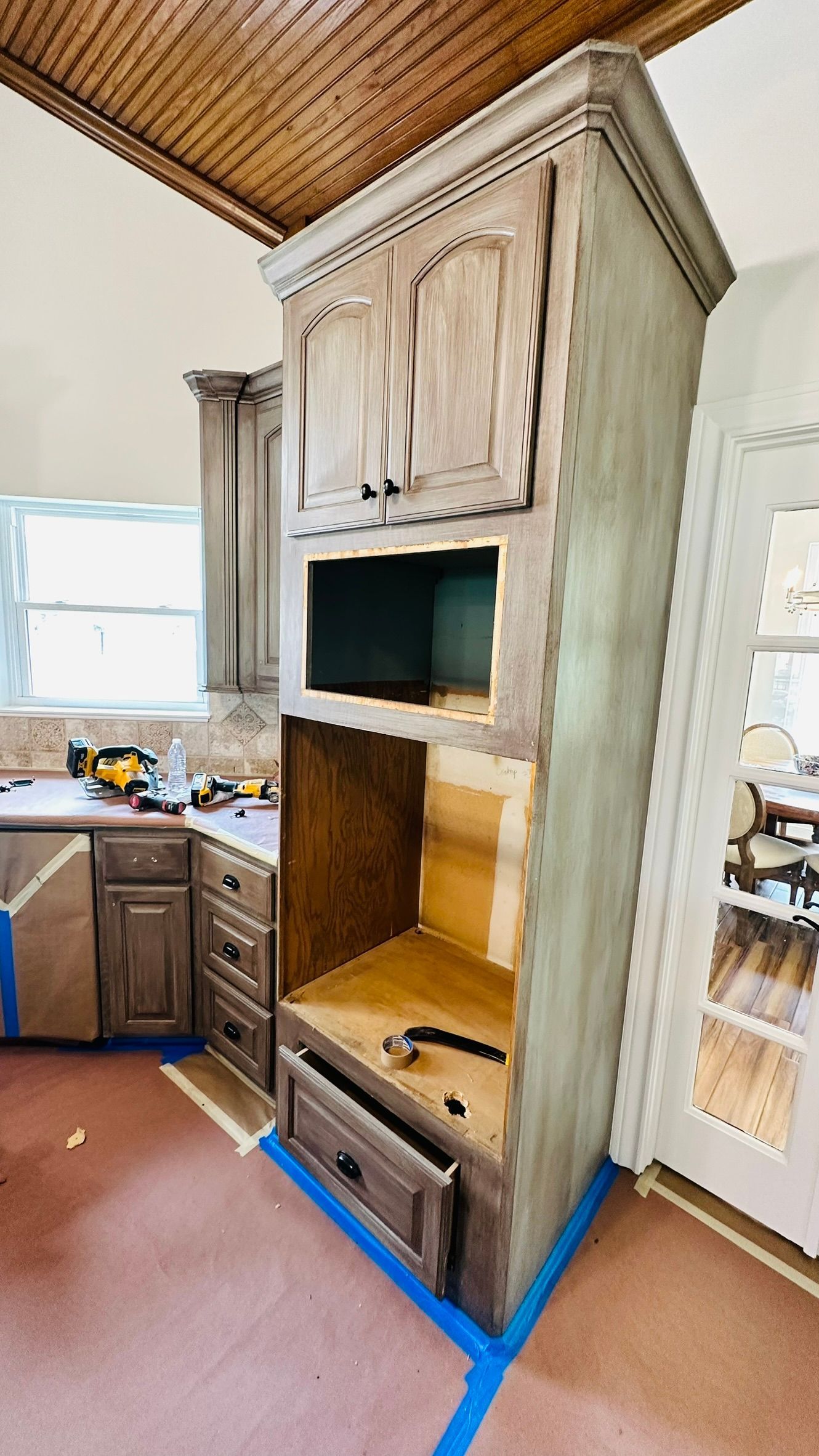 Kitchen cabinets being renovated; tall cabinet with microwave space.