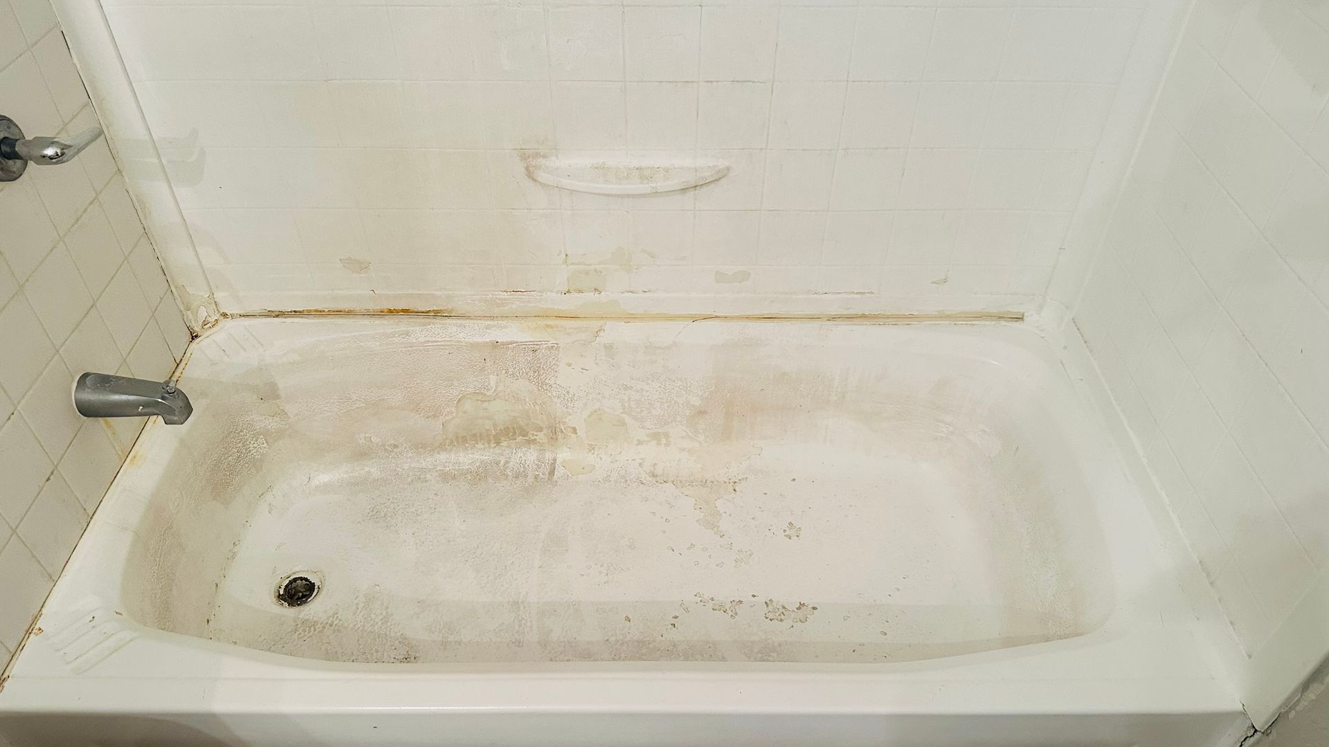 Dirty white bathtub with discoloration and grime.
