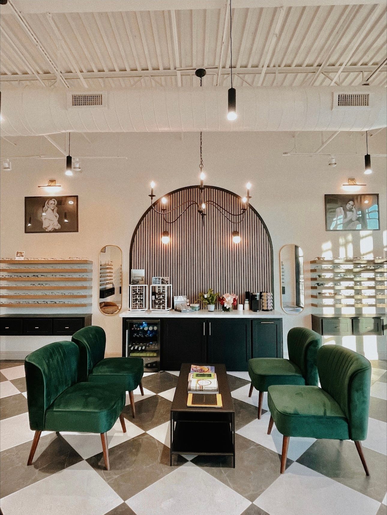 Interior of an optometry office with green velvet seating, a black and white checkered floor, and eyewear displays.