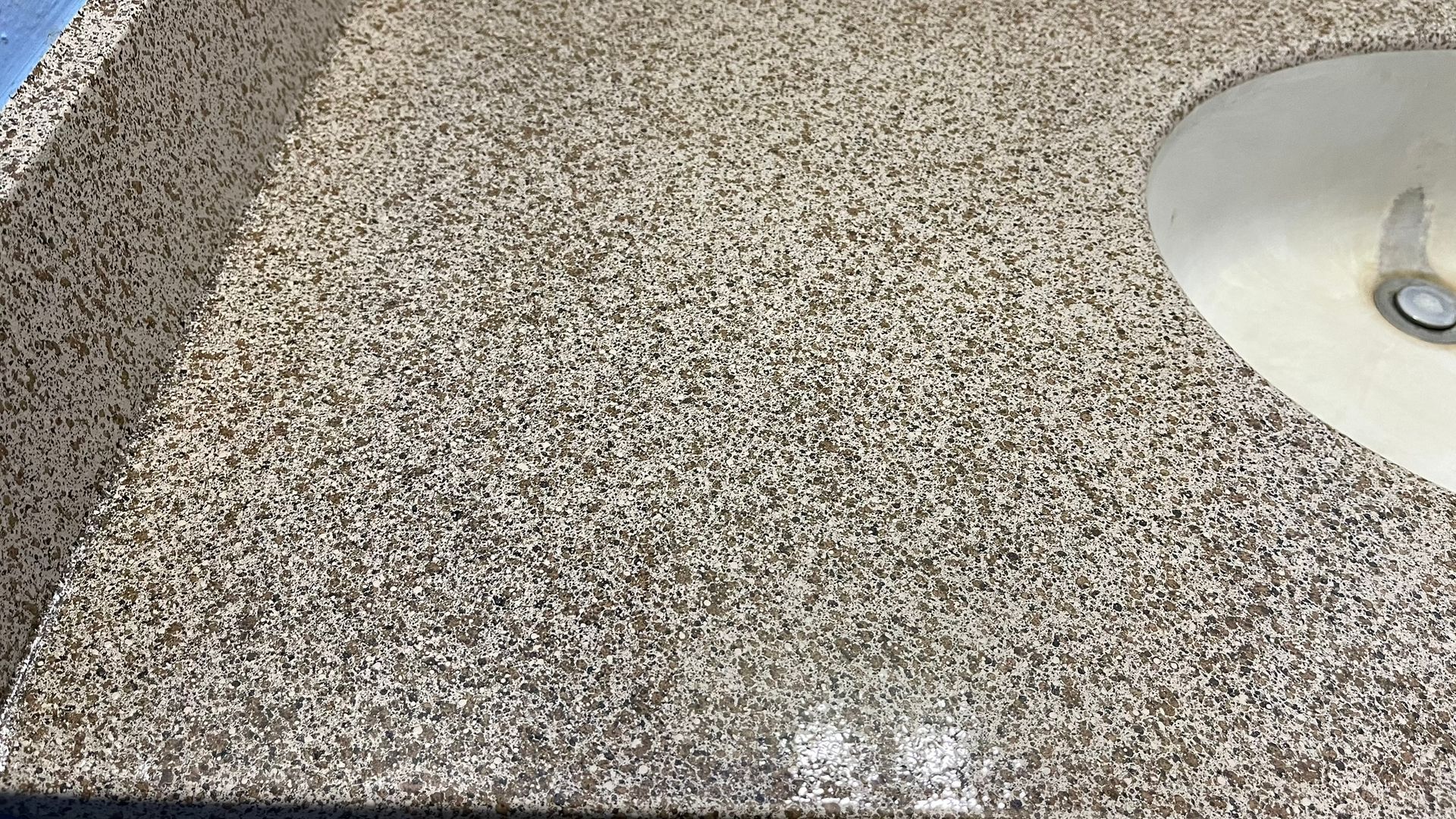 Close-up view of a textured light brown surface with a cymbal in the upper right corner.