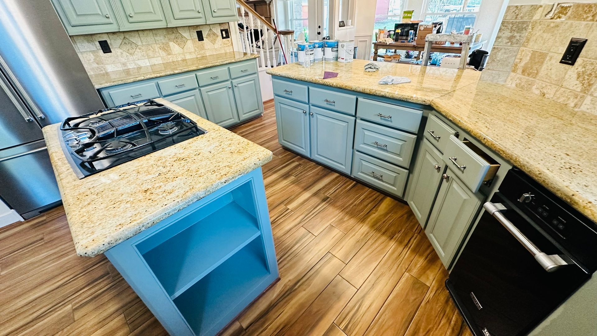 Kitchen with blue cabinets, beige countertops, and stainless steel appliances.