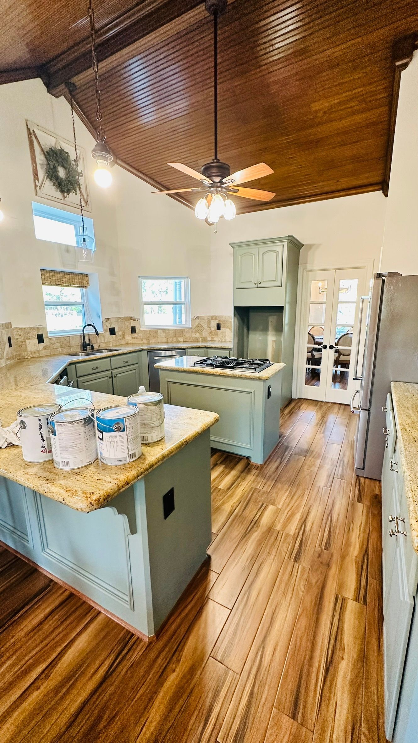 Kitchen with two light blue islands, granite countertops, wood floors, and a copper-colored ceiling.