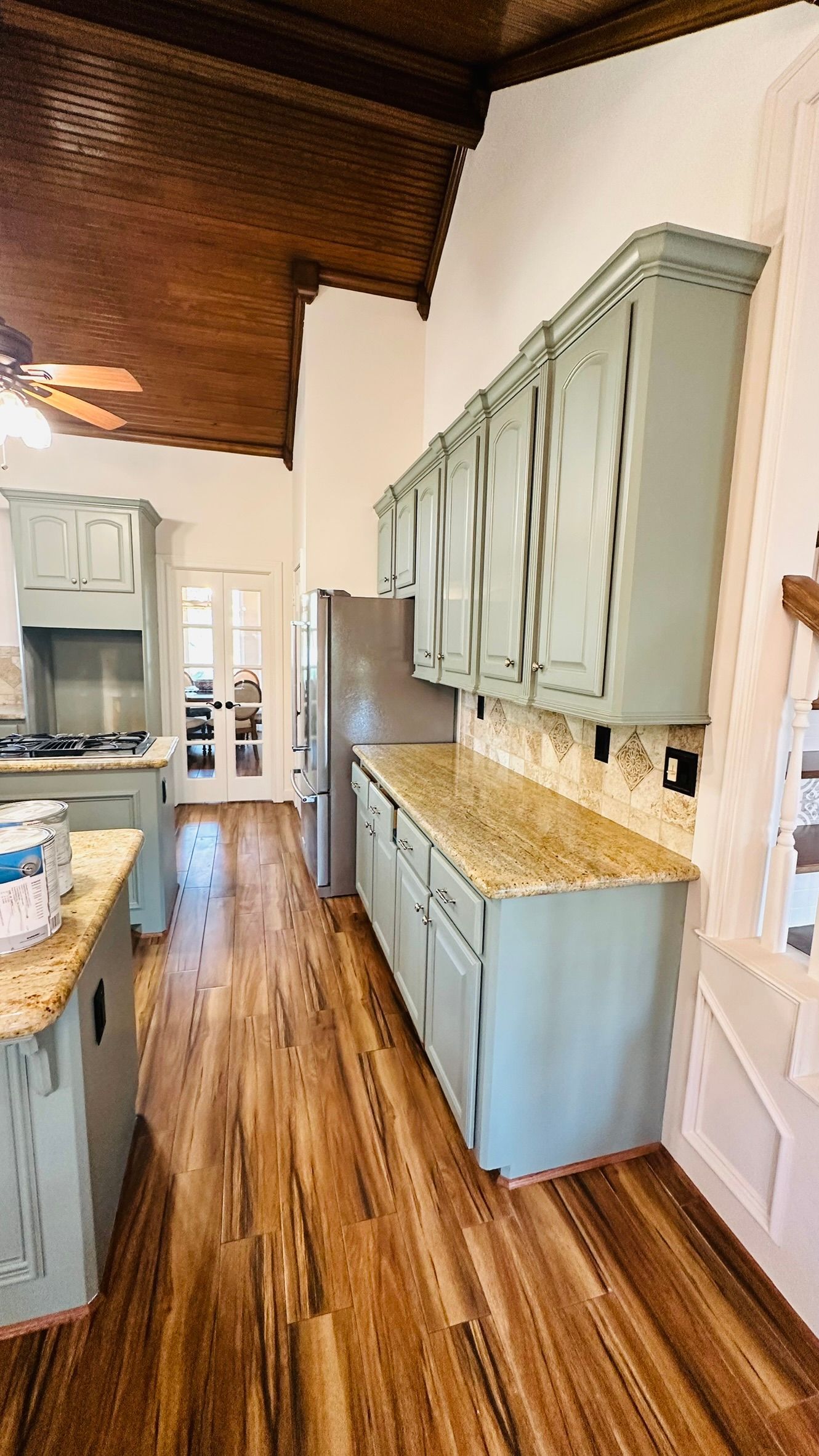 Kitchen with blue cabinets, wood floor, granite countertops, and stainless steel refrigerator.