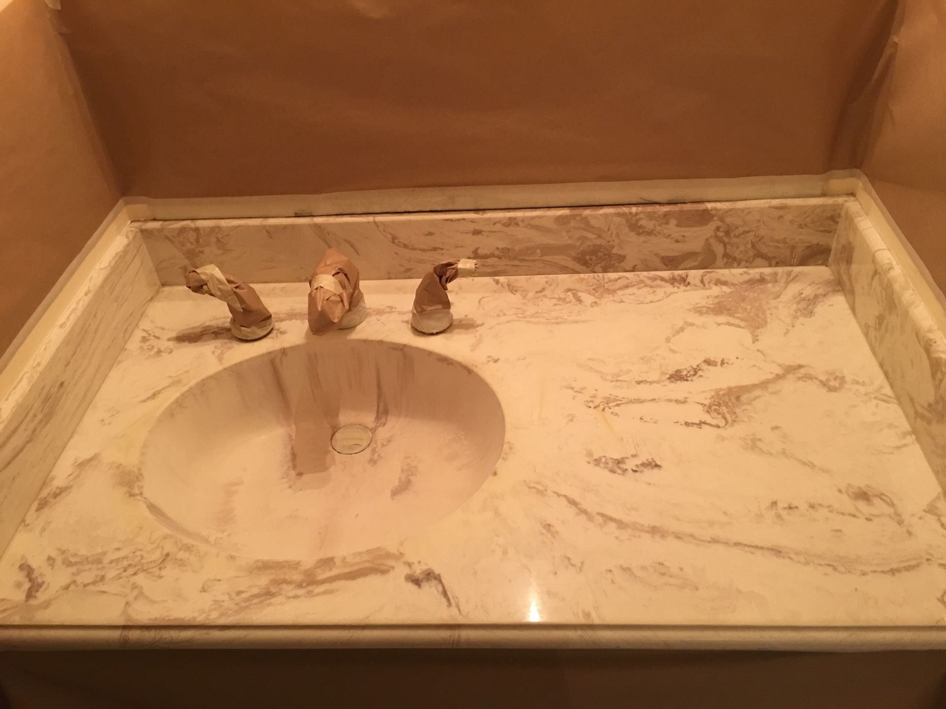 Marble vanity with an oval sink and three faucet handles.