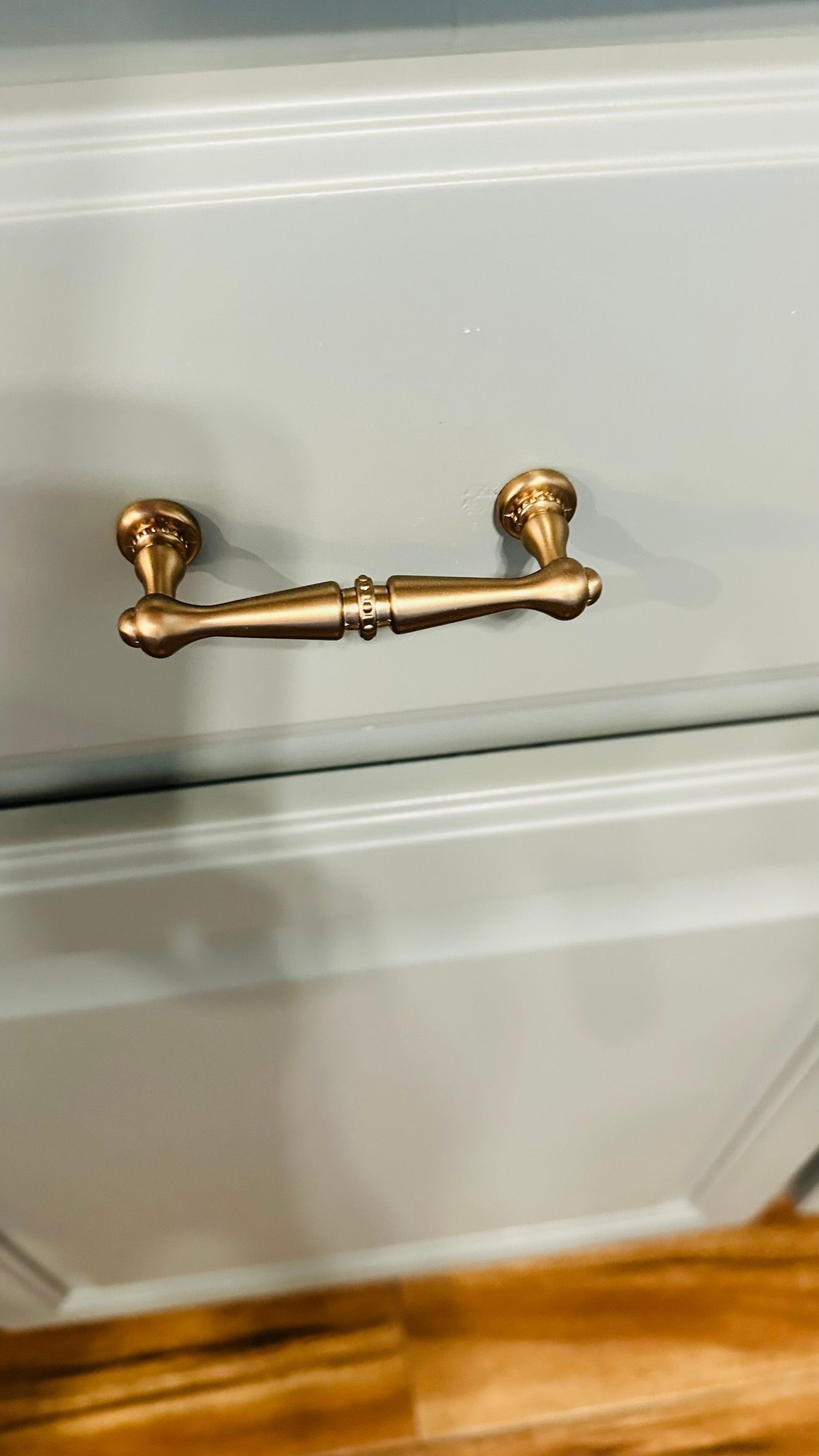 Brass drawer pull on a light blue painted dresser drawer.