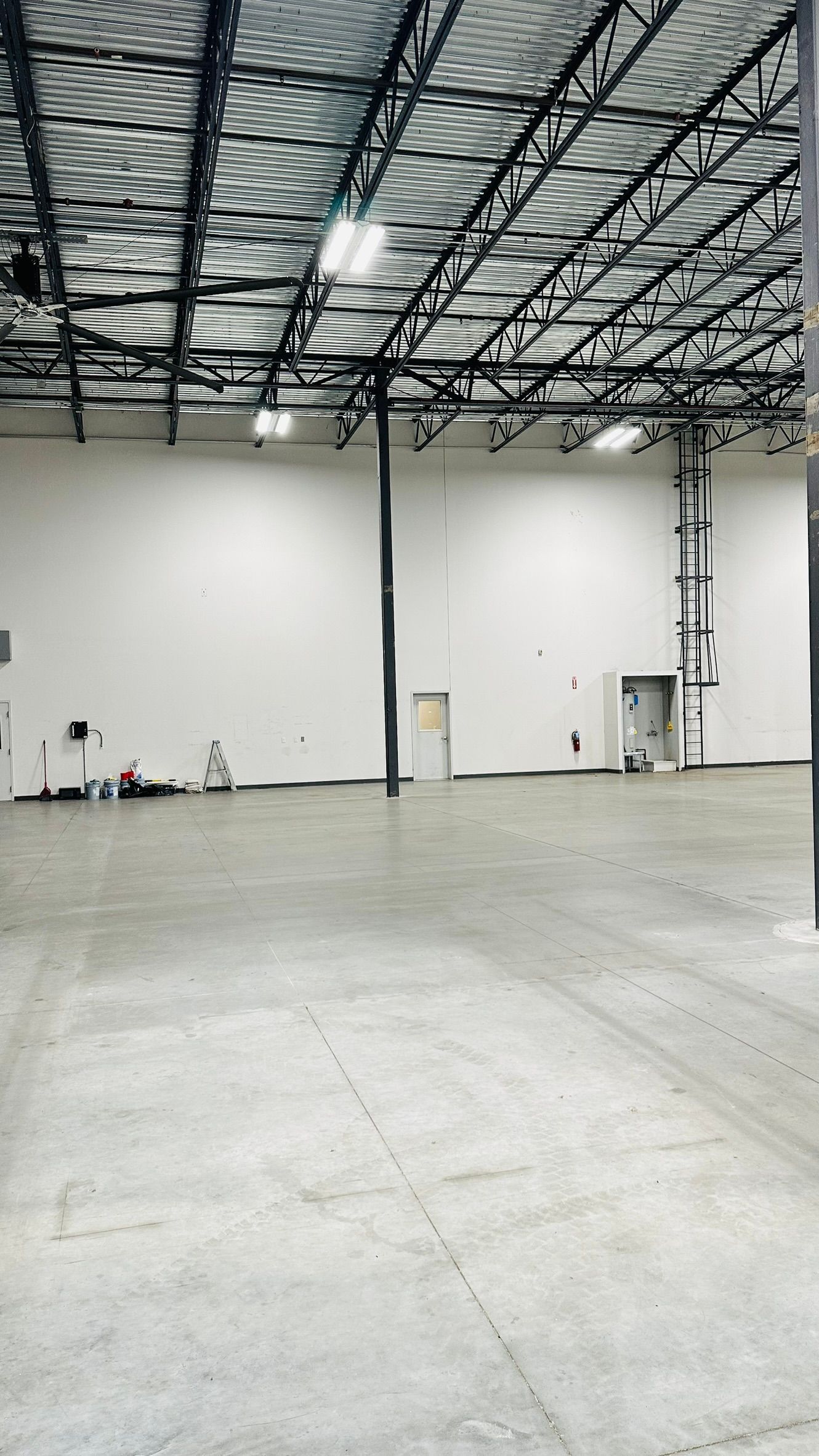 Large, empty warehouse interior with high ceilings, white walls, and a concrete floor.