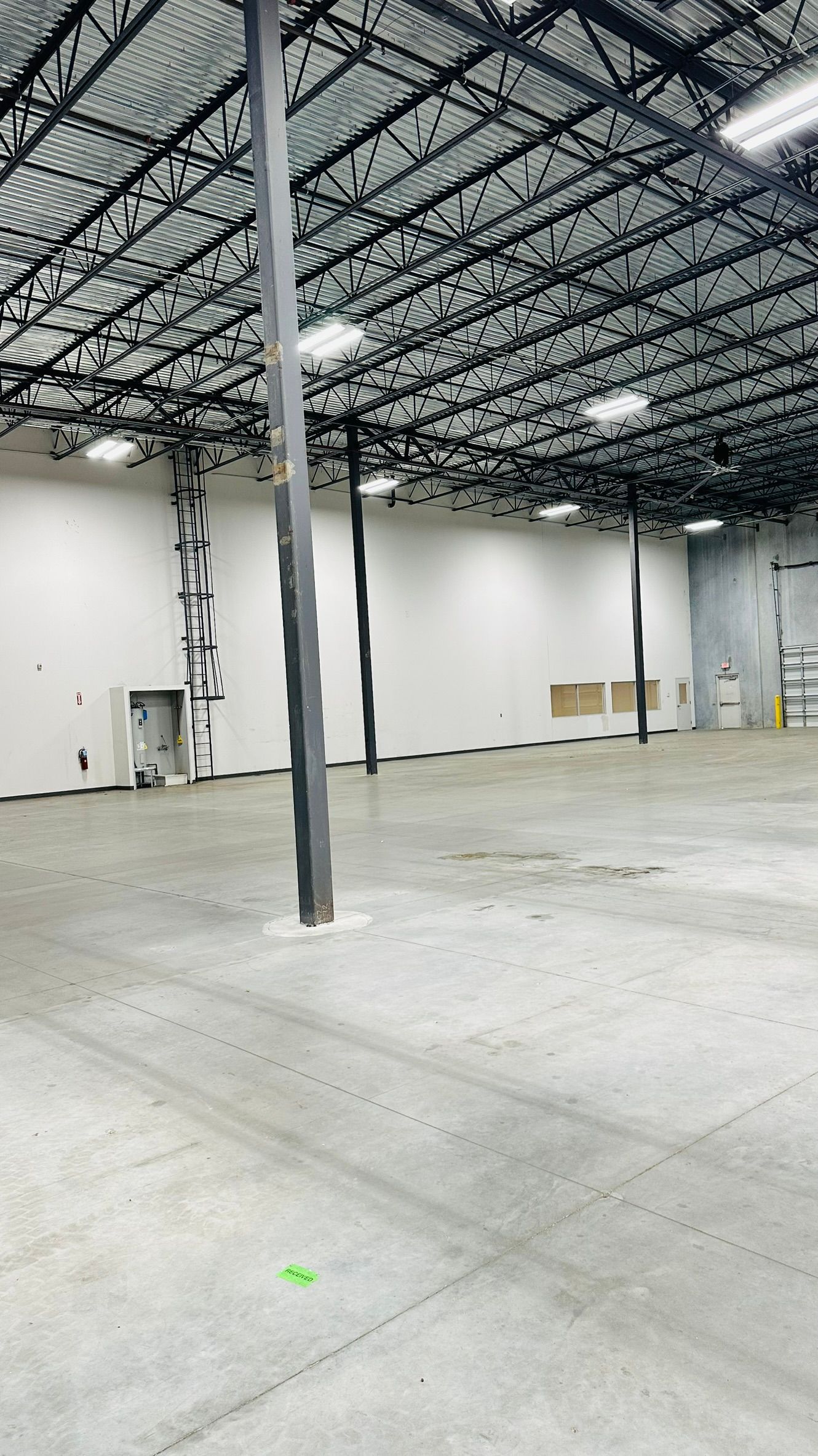Empty warehouse interior with metal beams, concrete floor, and white walls.