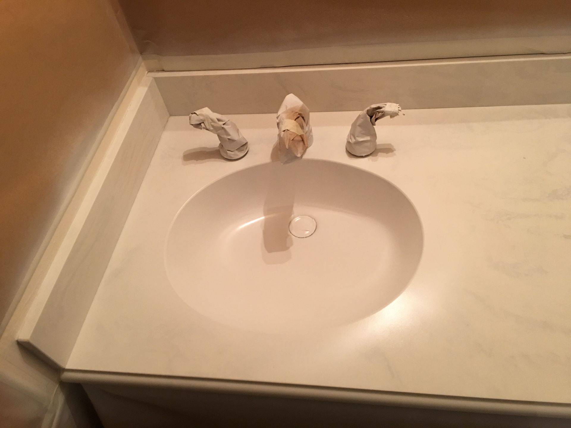 White oval bathroom sink with three-handled faucet on a marble countertop.