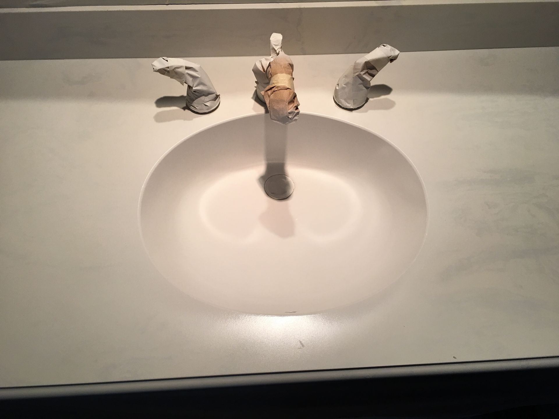 White bathroom sink with three faucet handles, centered above a white basin.