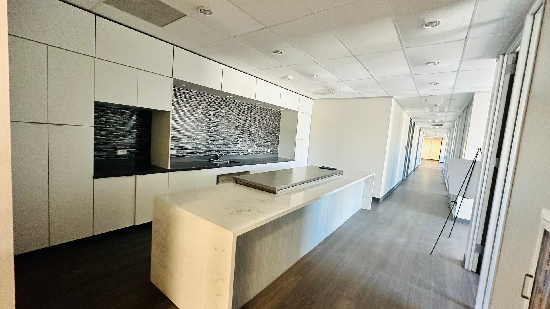 Modern kitchen with white cabinets, island, backsplash, and wood floor.