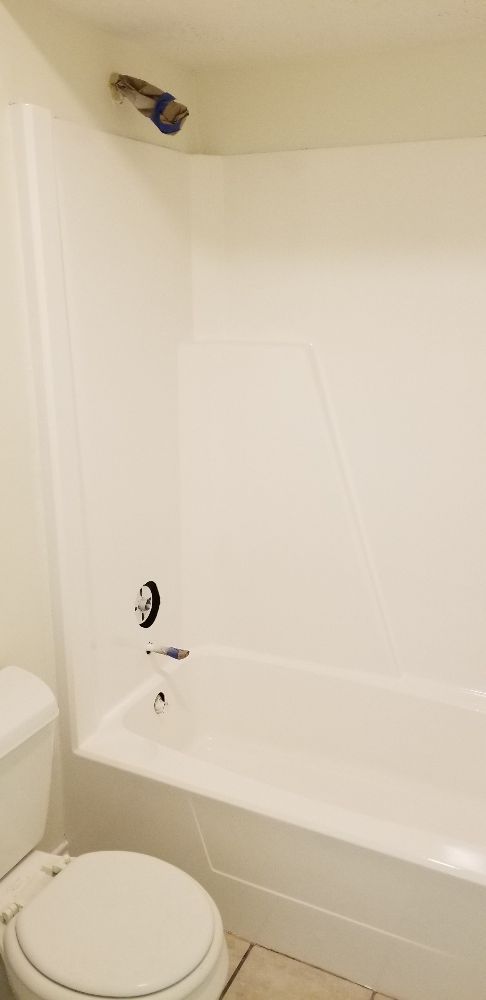 White bathroom with toilet, bathtub, and showerhead.