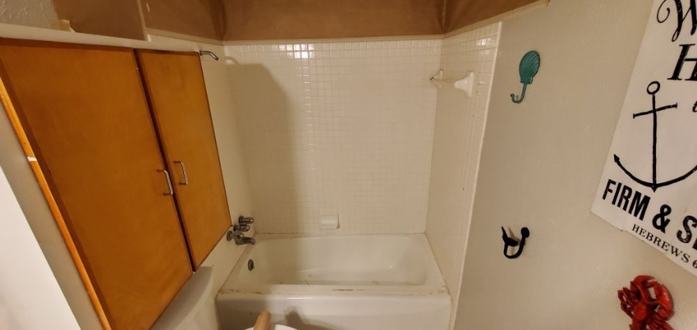 Bathroom with shower, wooden cabinet, and nautical decor.