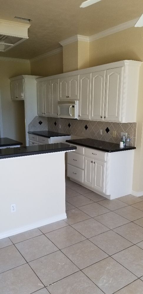 White kitchen cabinets, black countertops, tiled floor, and a kitchen island.