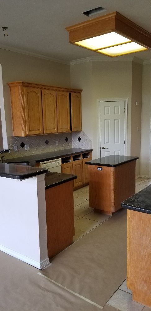 Kitchen with wood cabinets and black countertops. An island and a door are visible.