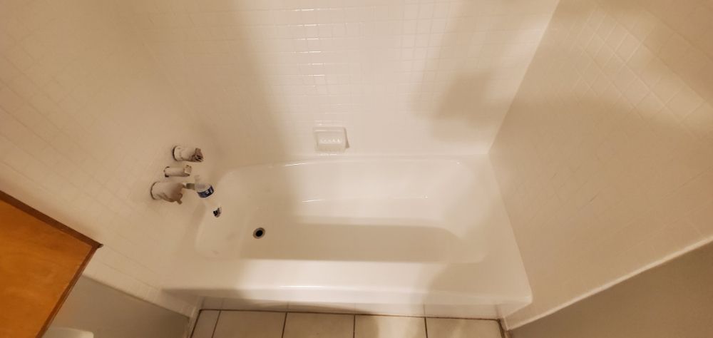 A white bathtub with silver faucet in a bathroom with beige walls.