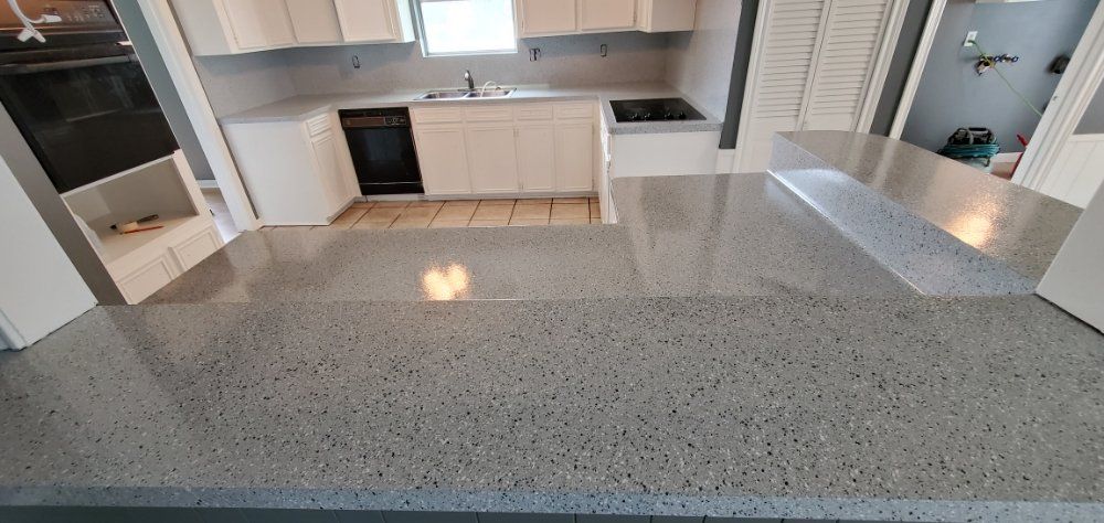 Kitchen with gray countertop, white cabinets, and a black oven.