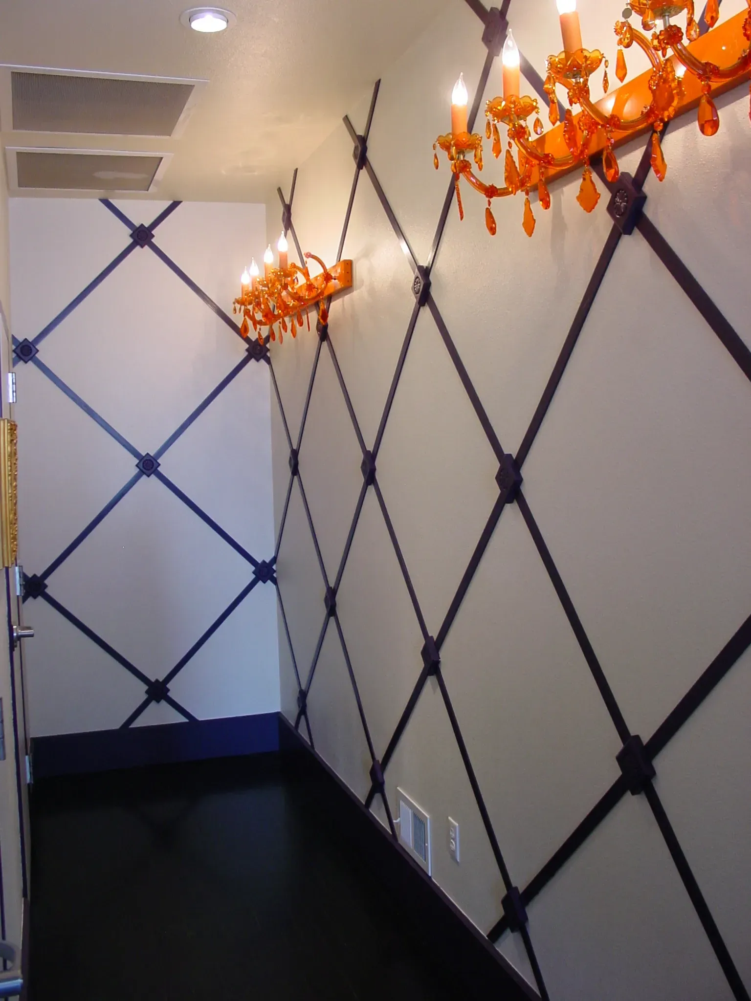 A room with a black and white wall and orange chandeliers