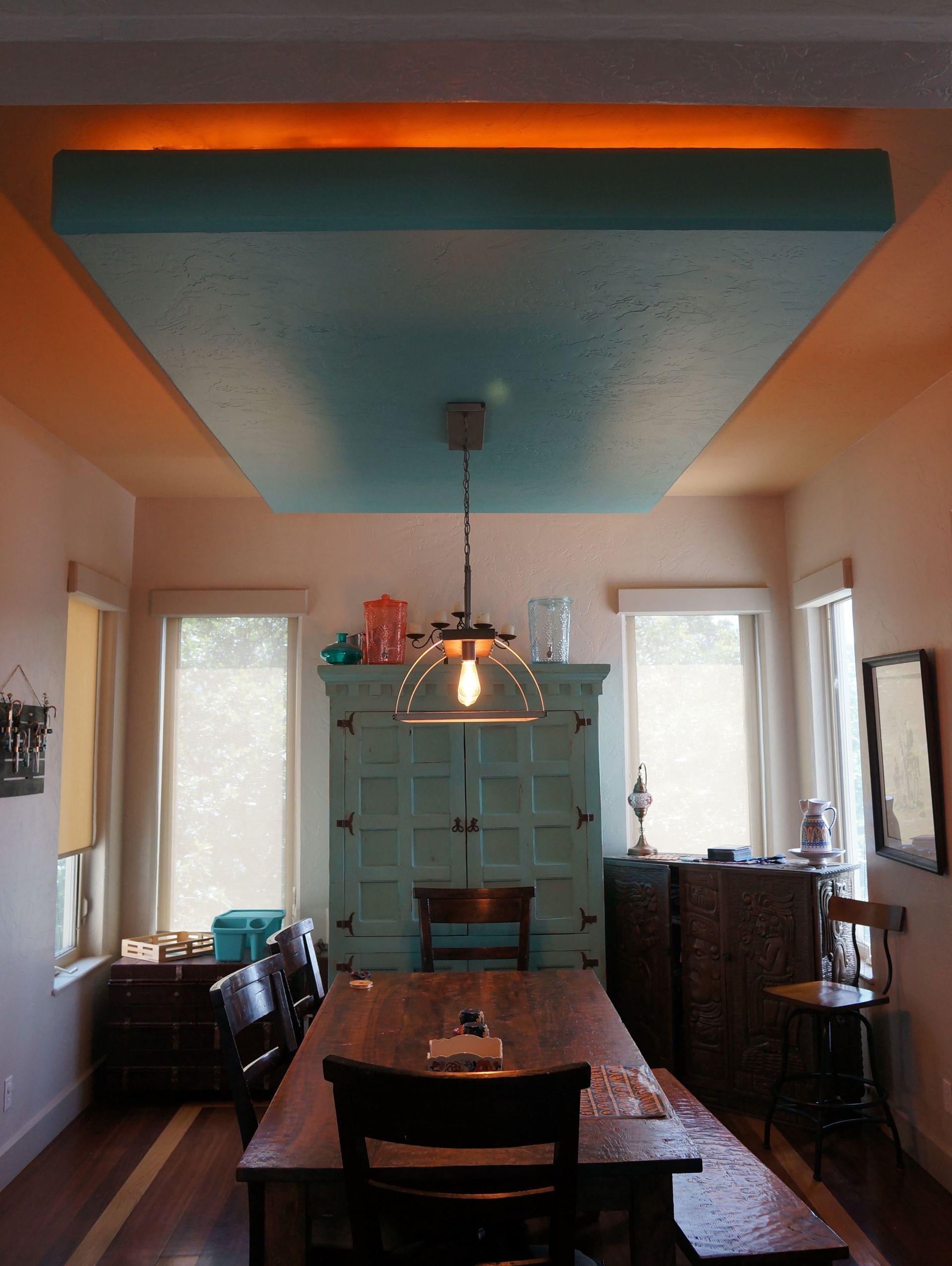 A dining room with a table and chairs and a light on the ceiling