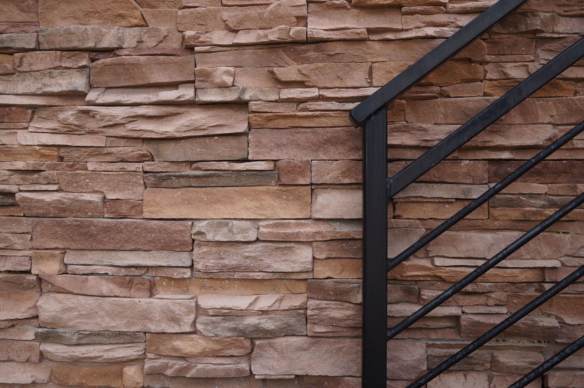 A stone wall with a black railing in front of it