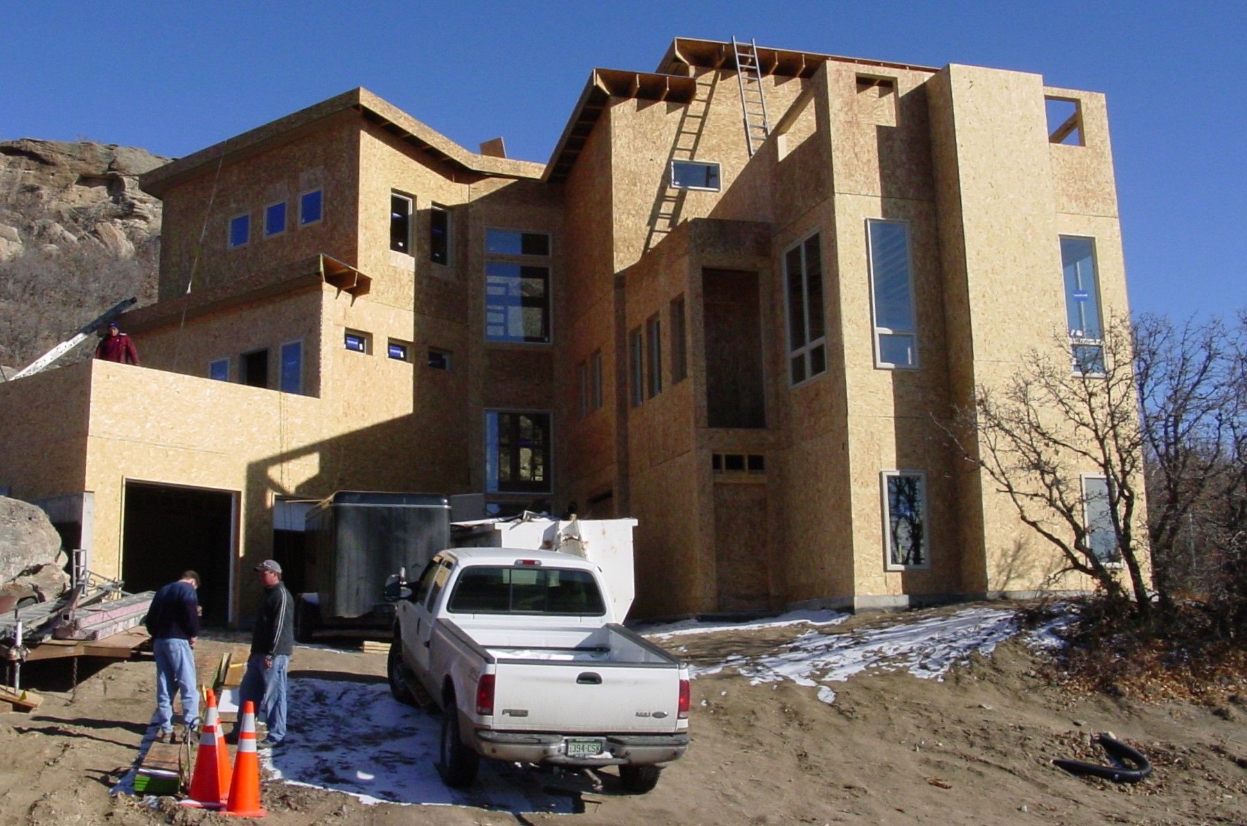 A white truck is parked in front of a large house under construction