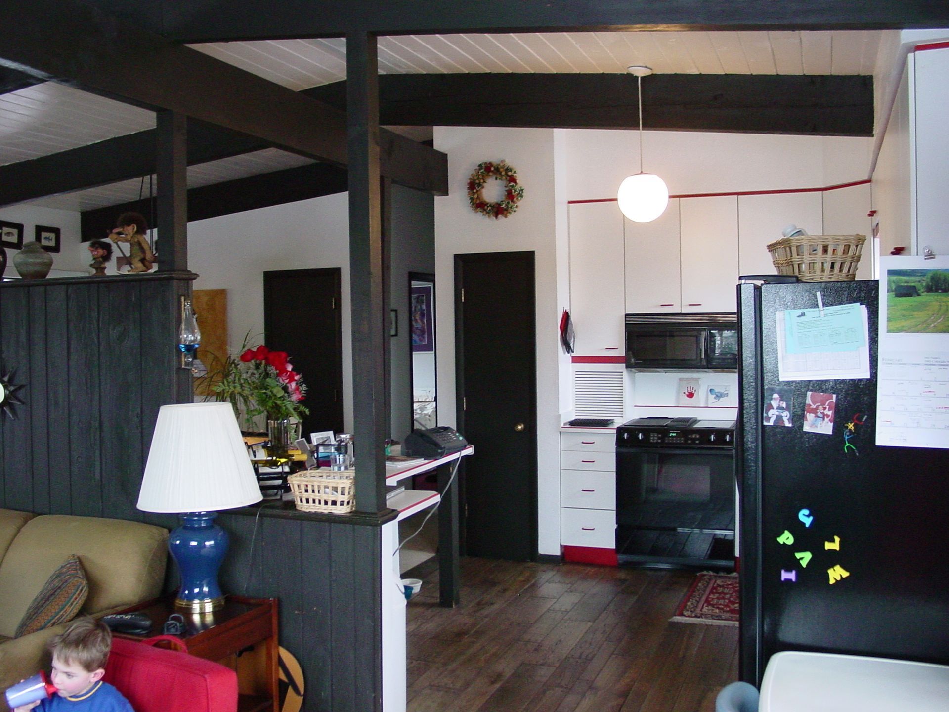 A living room with a lamp and a black refrigerator