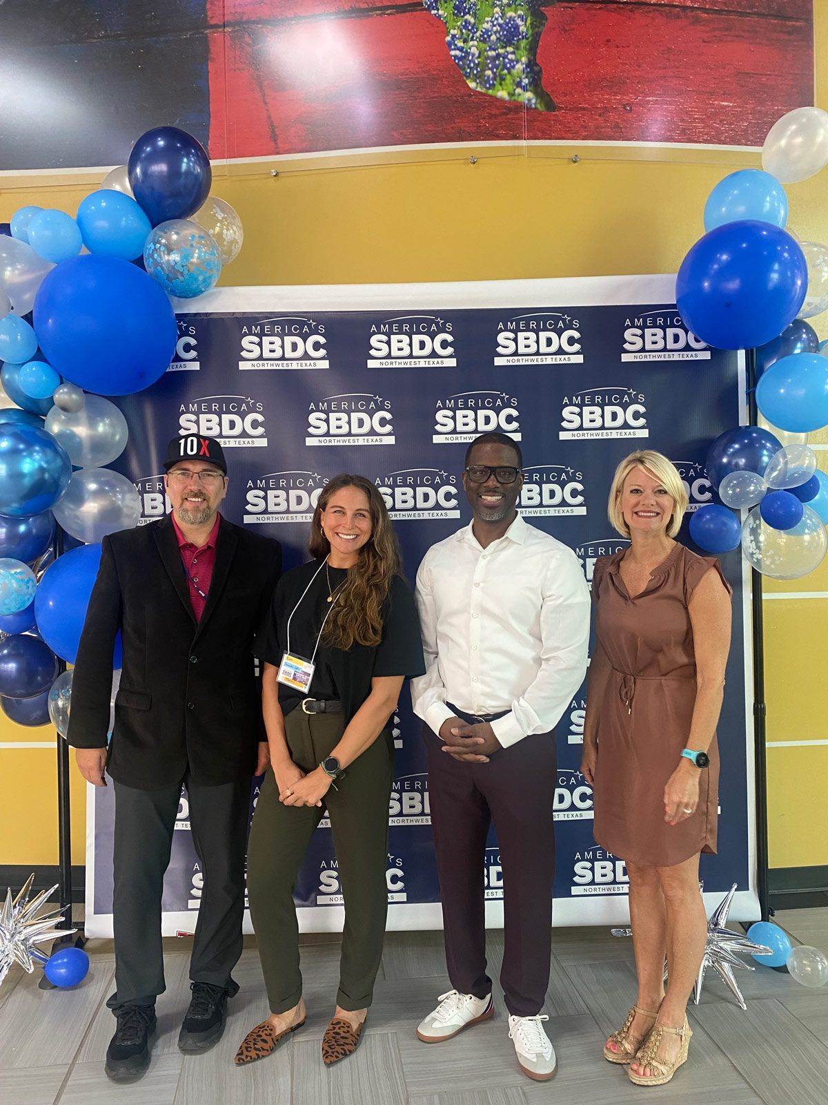 Two men and two women standing in front of a blue backdrop — Thryv Foundation