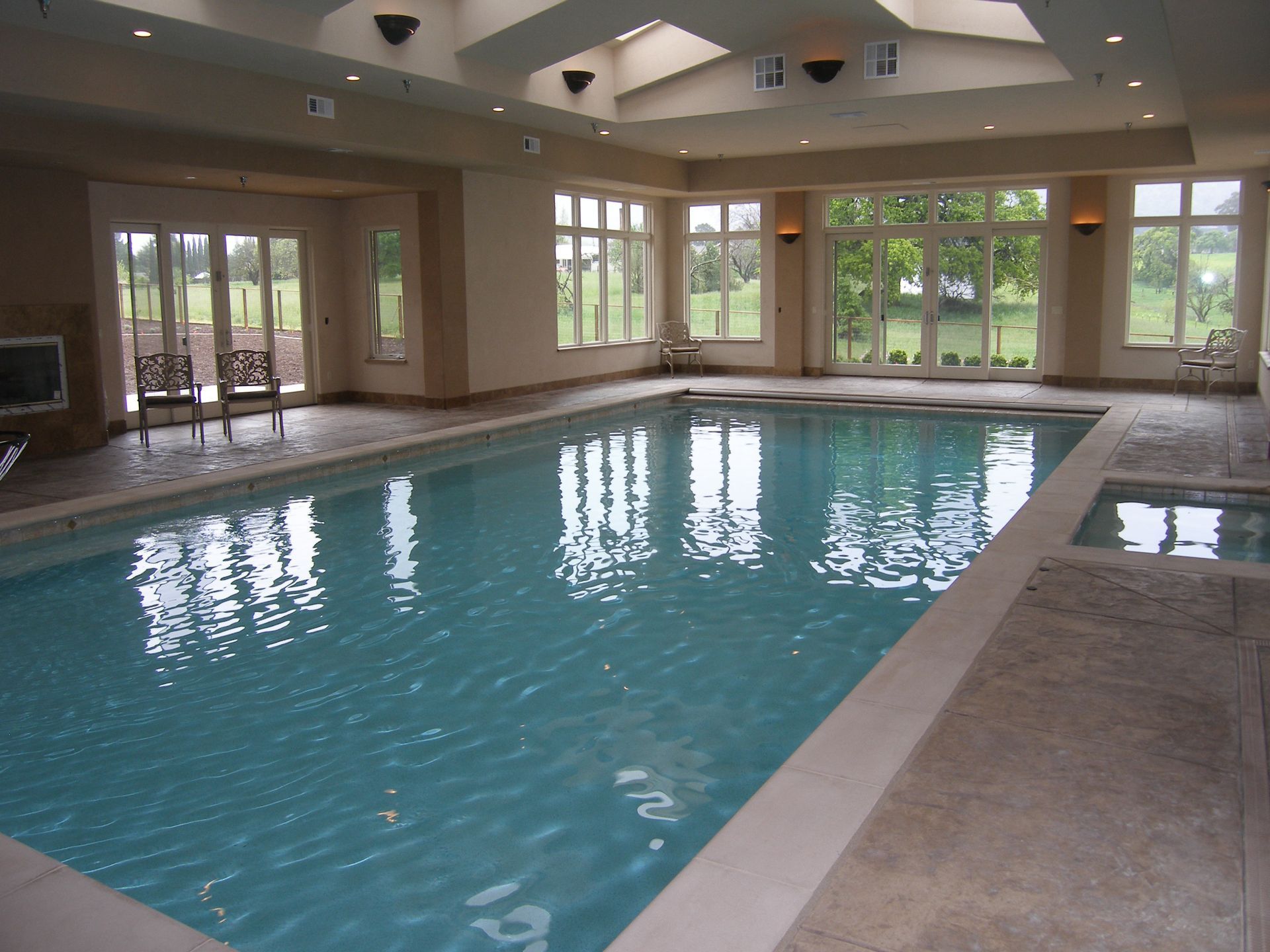 Indoor swimming pool with large windows and a tan tiled deck