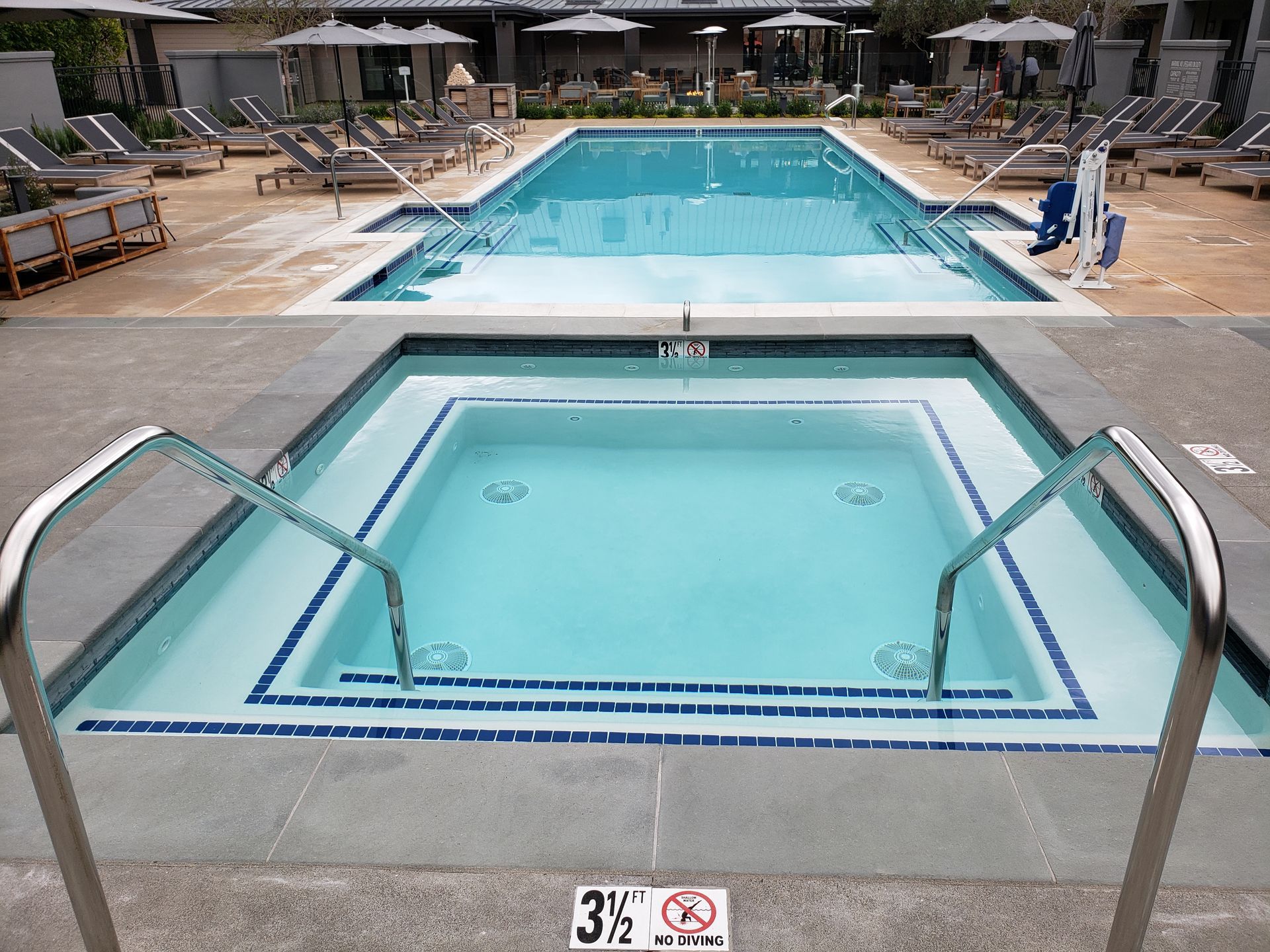 Accessible pool with a blue swimming lane and a small ramped spa in the foreground