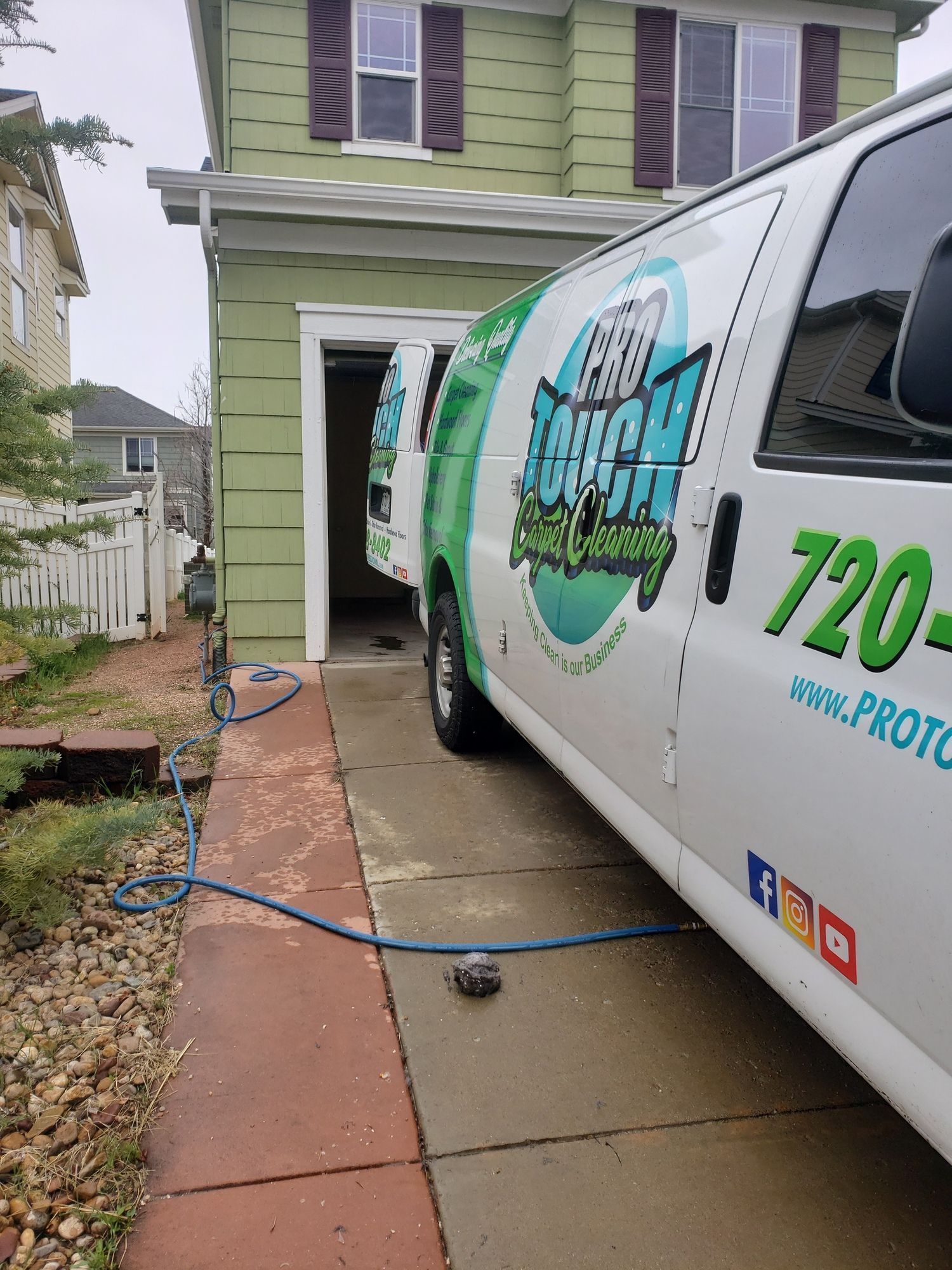 A green and white van is parked in front of a house.