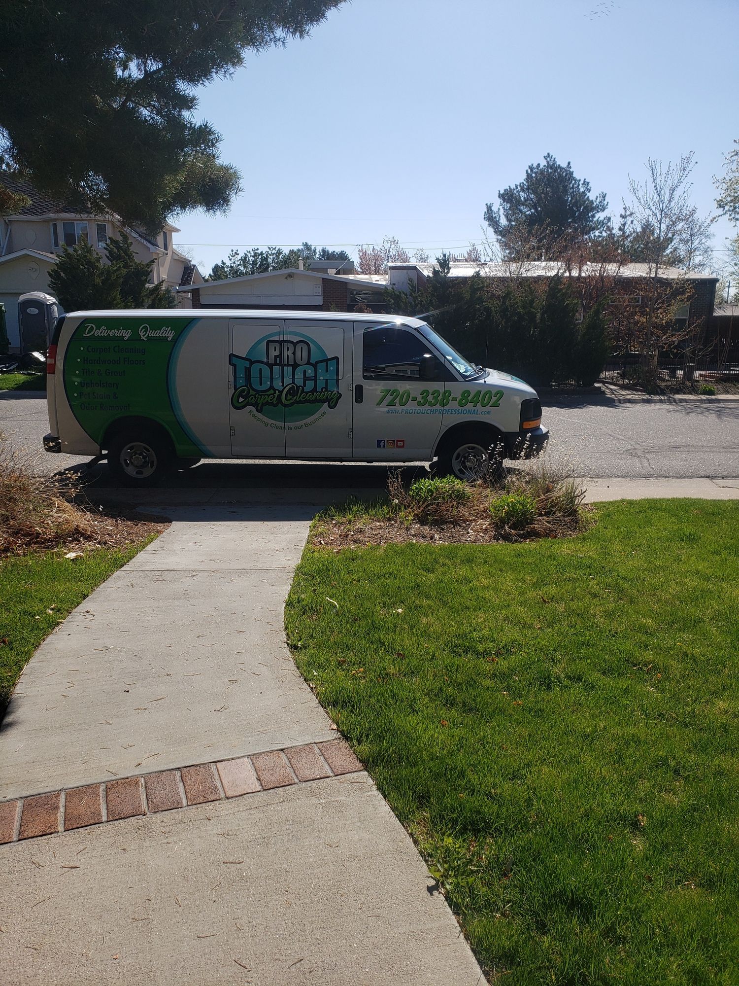 A white van is parked on the side of the road next to a sidewalk.