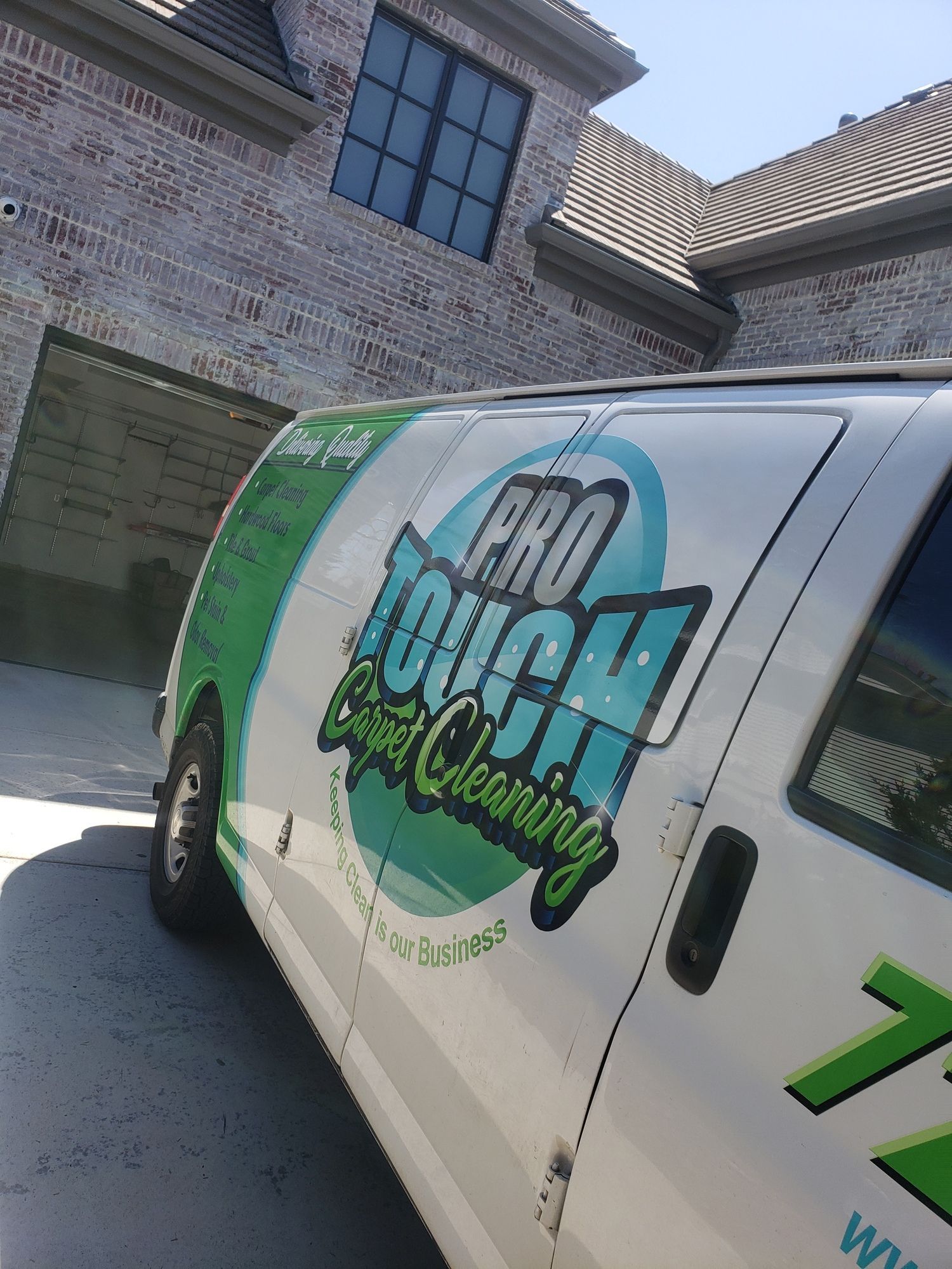 A pro touch cleaning van is parked in front of a brick building.