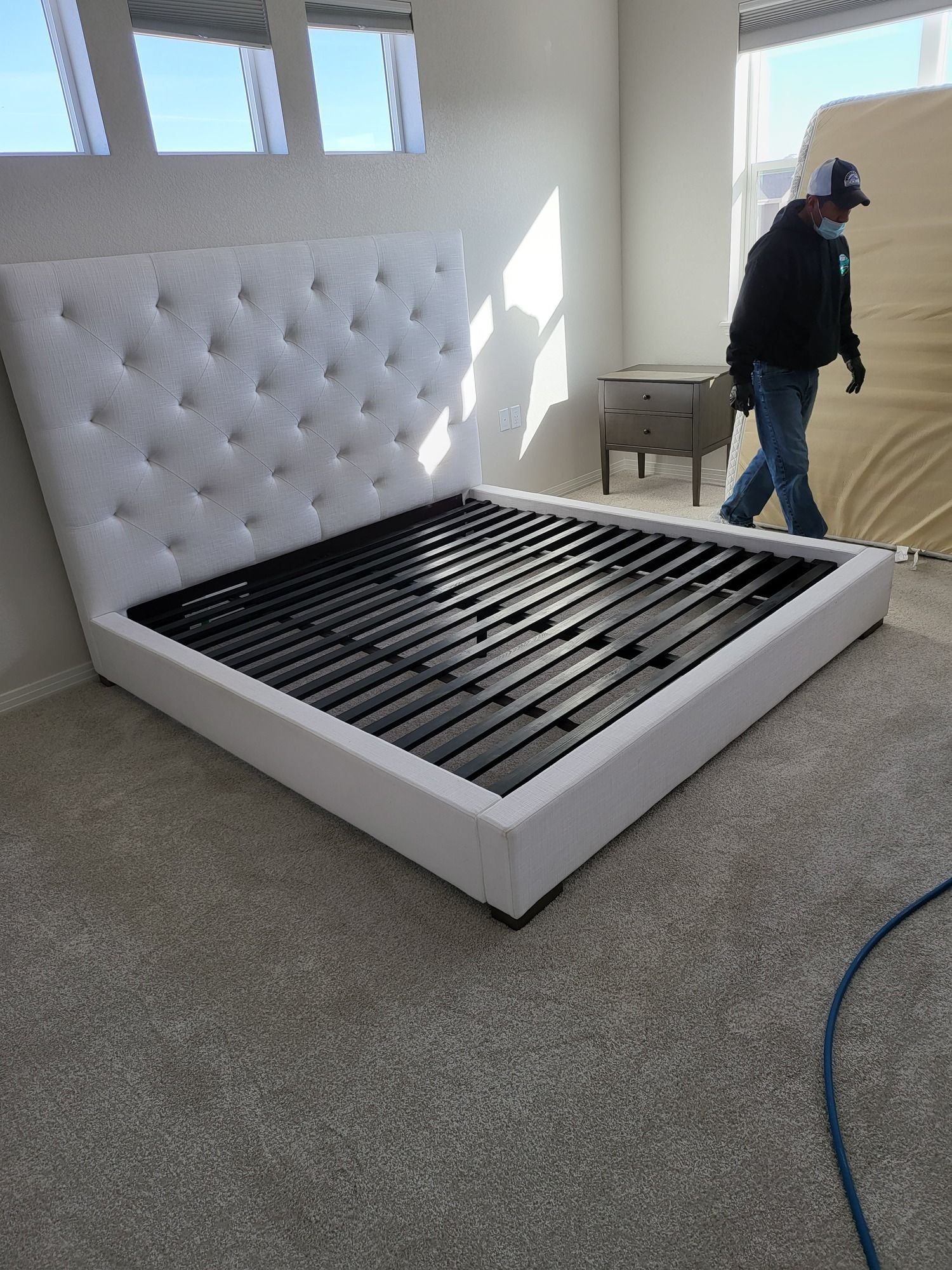 A man is standing next to a bed in a bedroom.