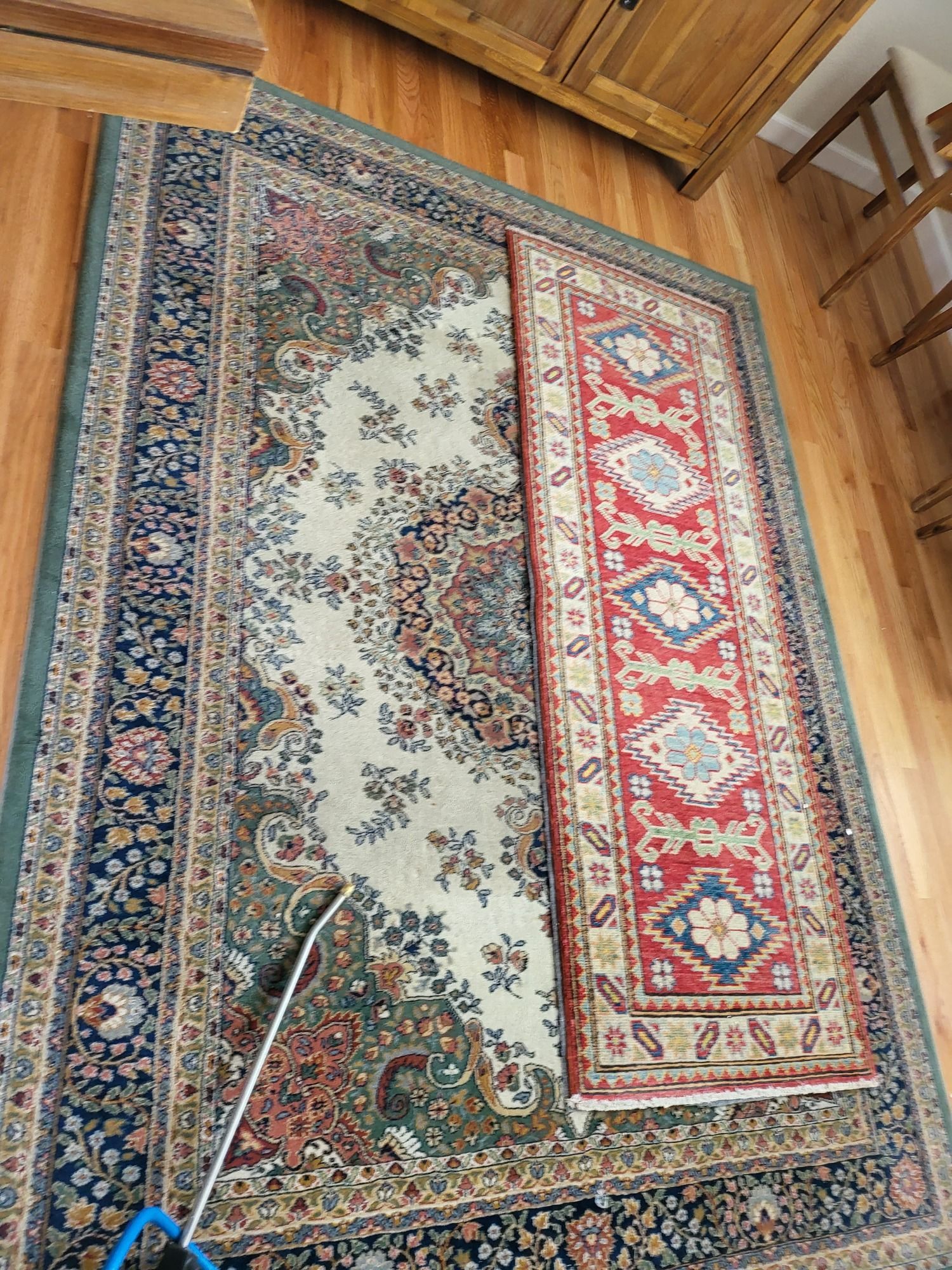 Two rugs are sitting on top of each other on a wooden floor.