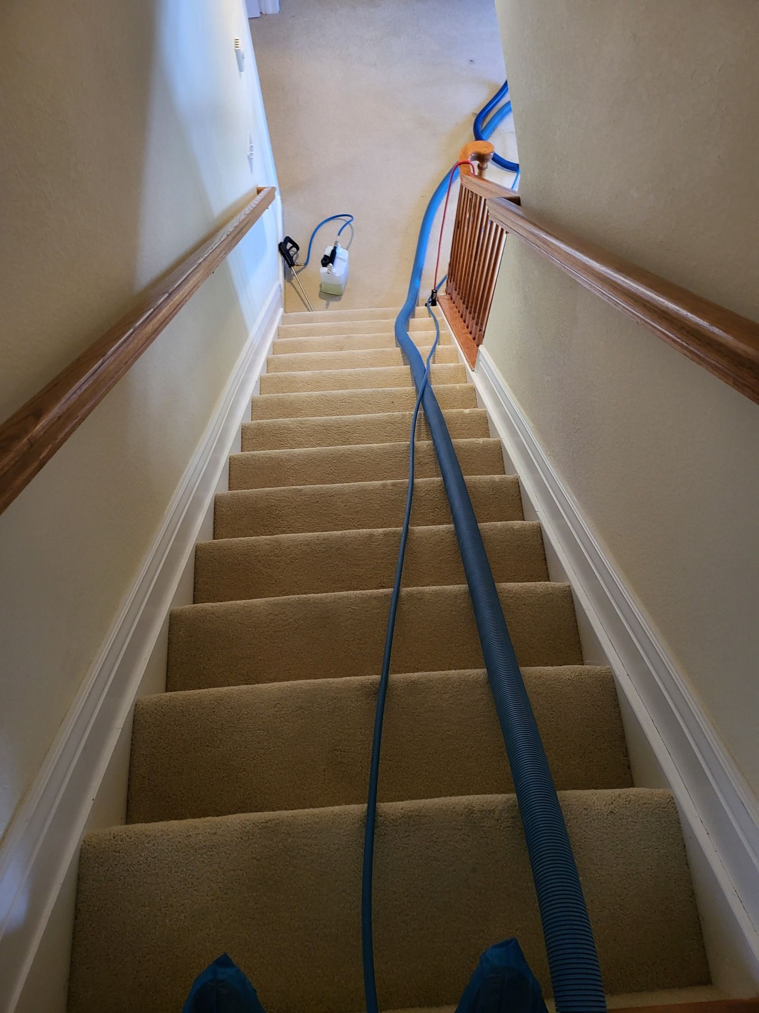 A person is standing on a set of stairs with a blue hose attached to them.