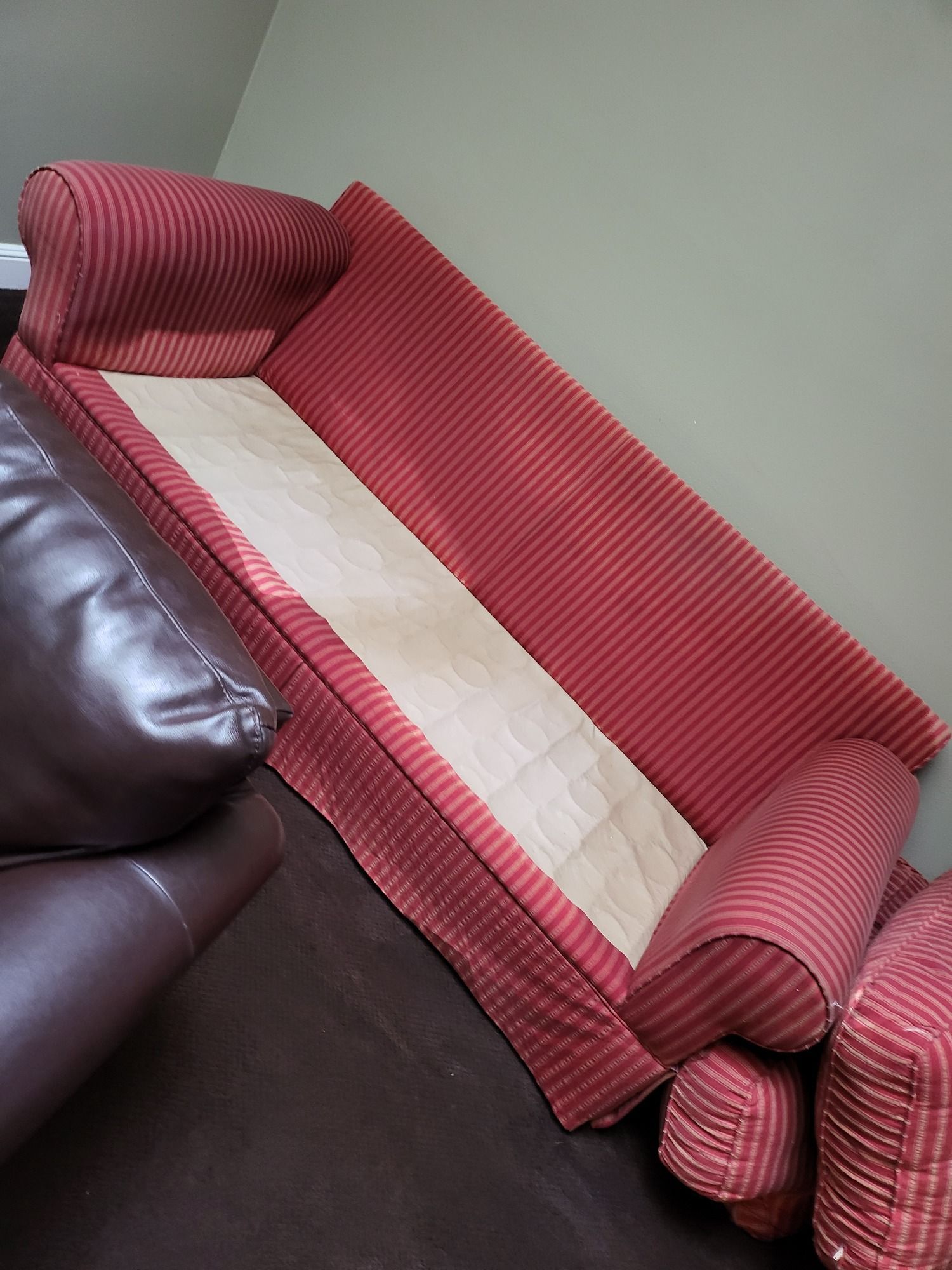 A red striped couch is laying on its side in a living room