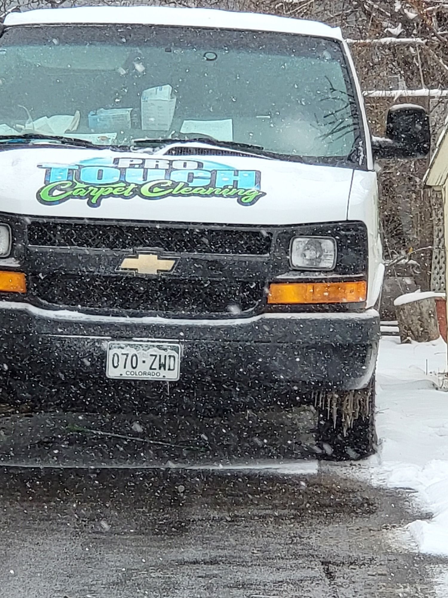 A white van is parked on the side of the road in the snow.