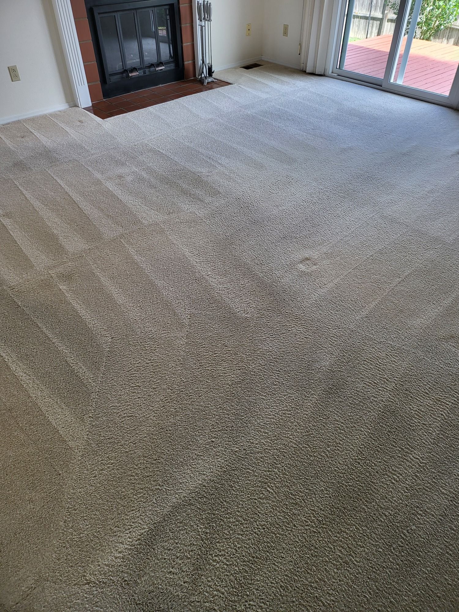 A living room with a fireplace and a large carpeted floor.