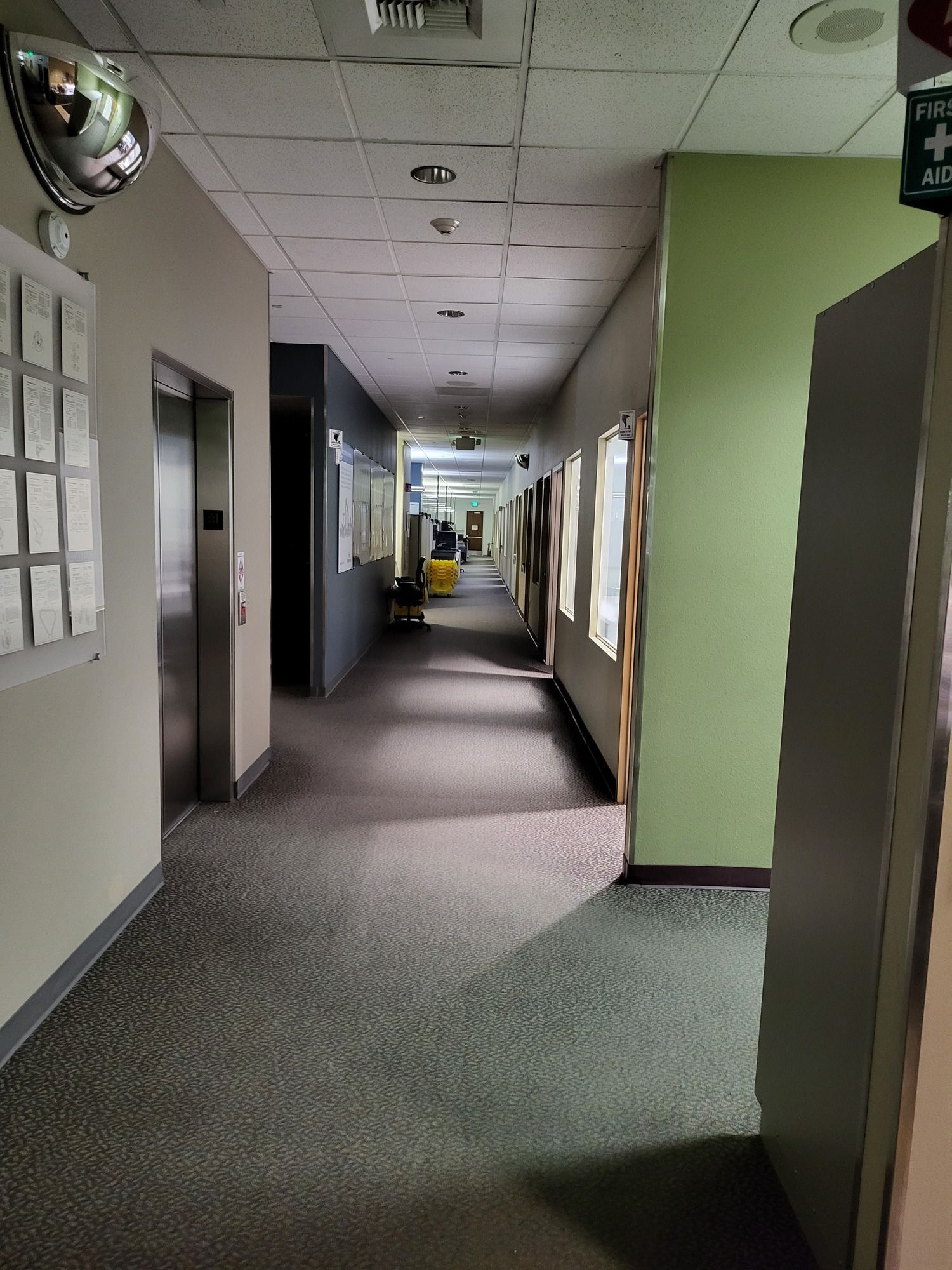 A long hallway in an office building with a mirror on the wall.