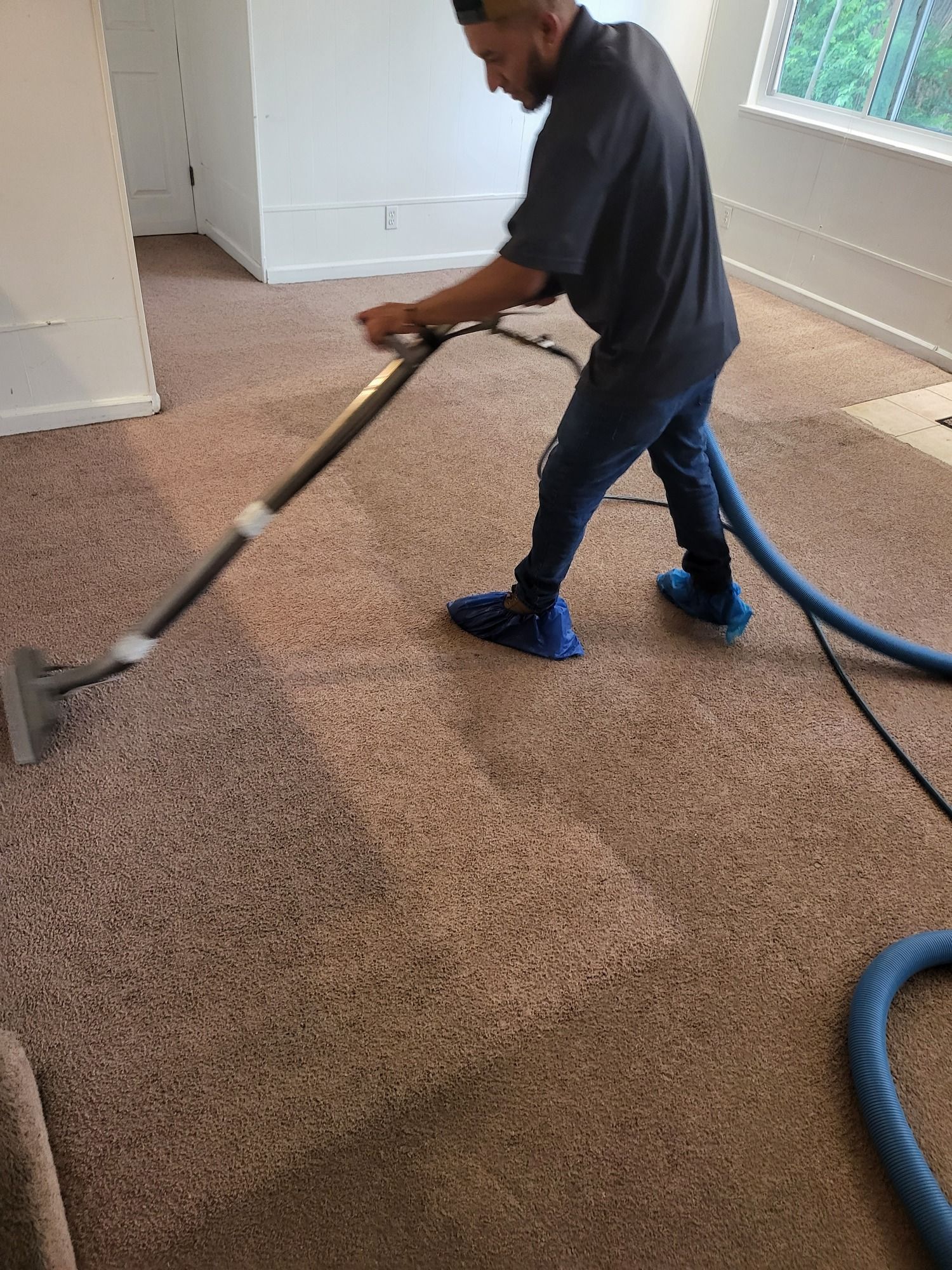 A man is using a vacuum cleaner to clean a carpet in a living room.