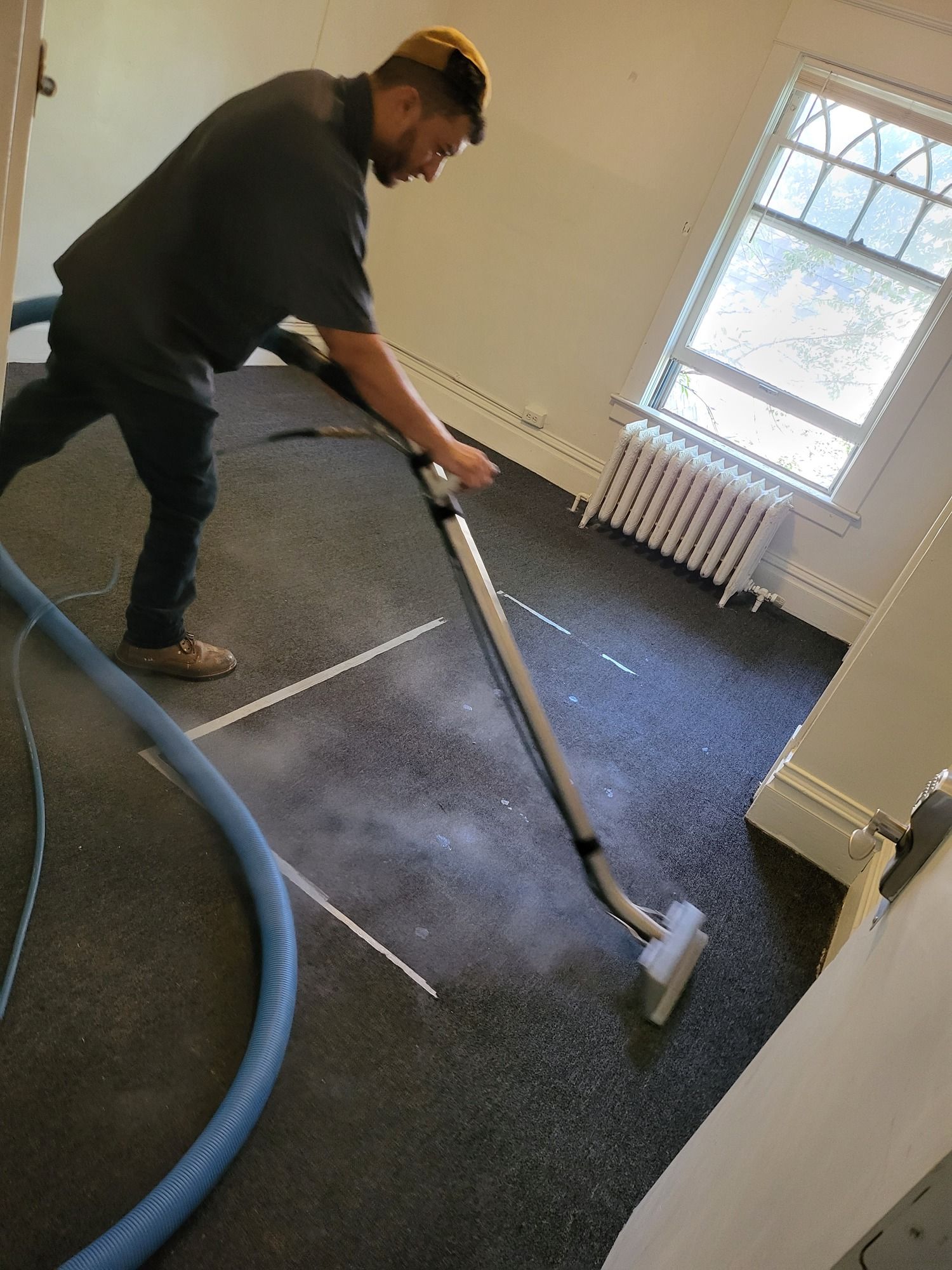 A man is using a vacuum cleaner to clean a carpet in a room.